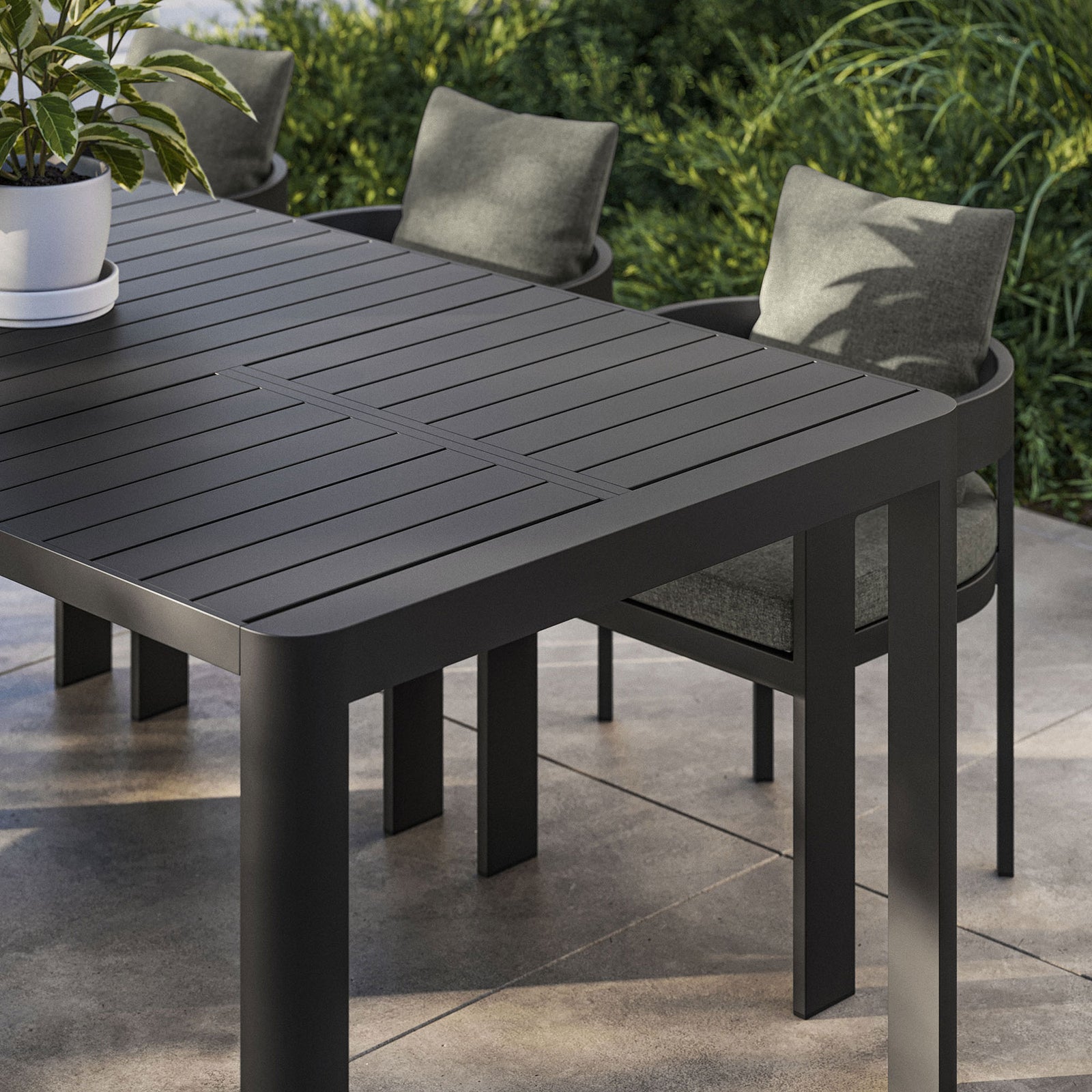 Tahoe dining table corner styled with planters and chairs, showcasing its sleek gray finish. || EEI-7236-GRY || detail_room