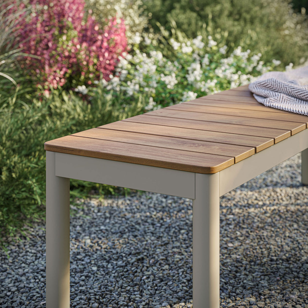 Finn outdoor bench with natural-look slatted top styled on a gravel patio beside lush greenery || EEI-7238-NAT || detail_room