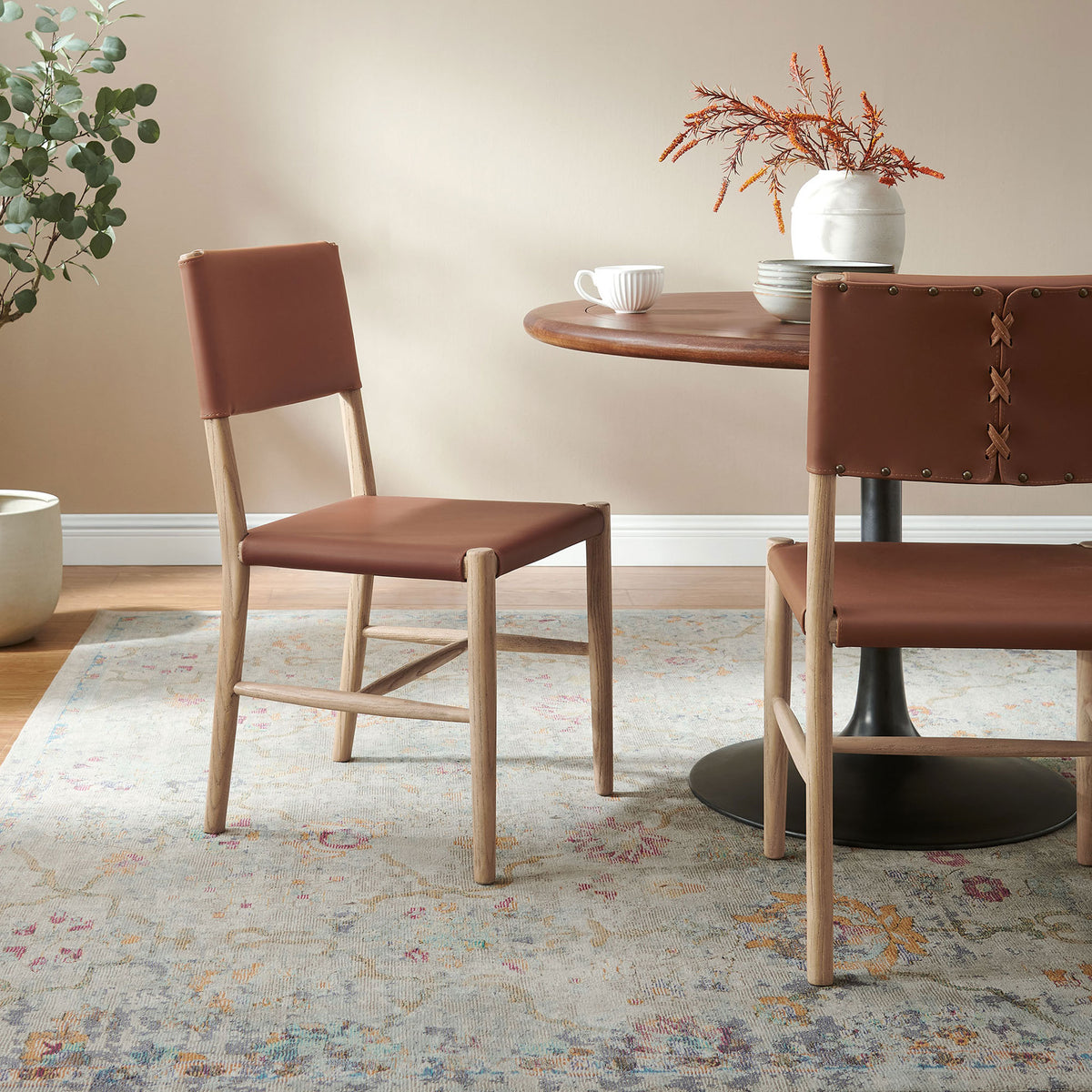 Pair of vegan leather dining chairs styled with a round wood table to create a warm, inviting breakfast nook || EEI-7240-NAT-SDL || front_angle_multi_room