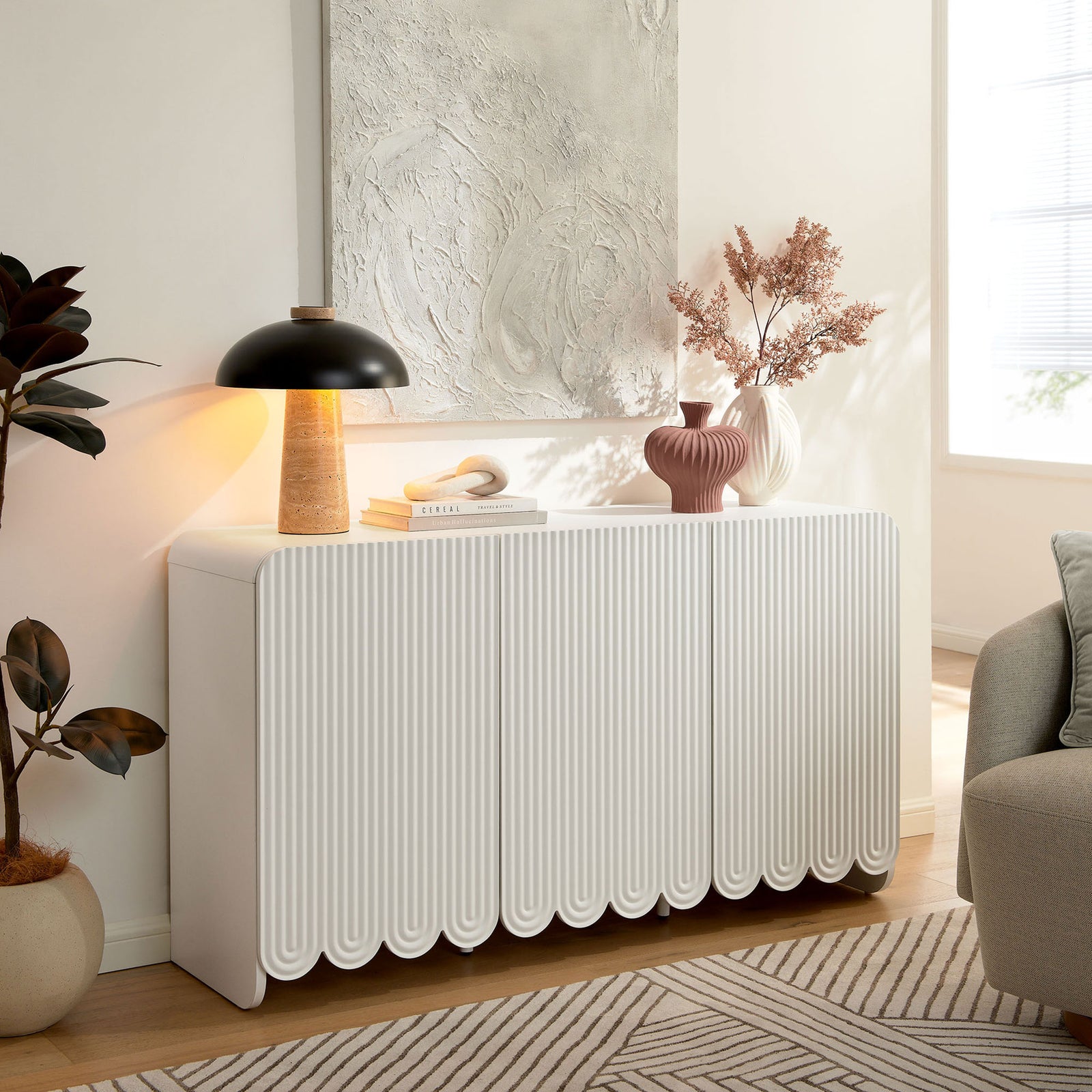 White fluted sideboard styled in a bright living room with art, lighting, and decorative accents || EEI-7241-WHI || front_angle_room