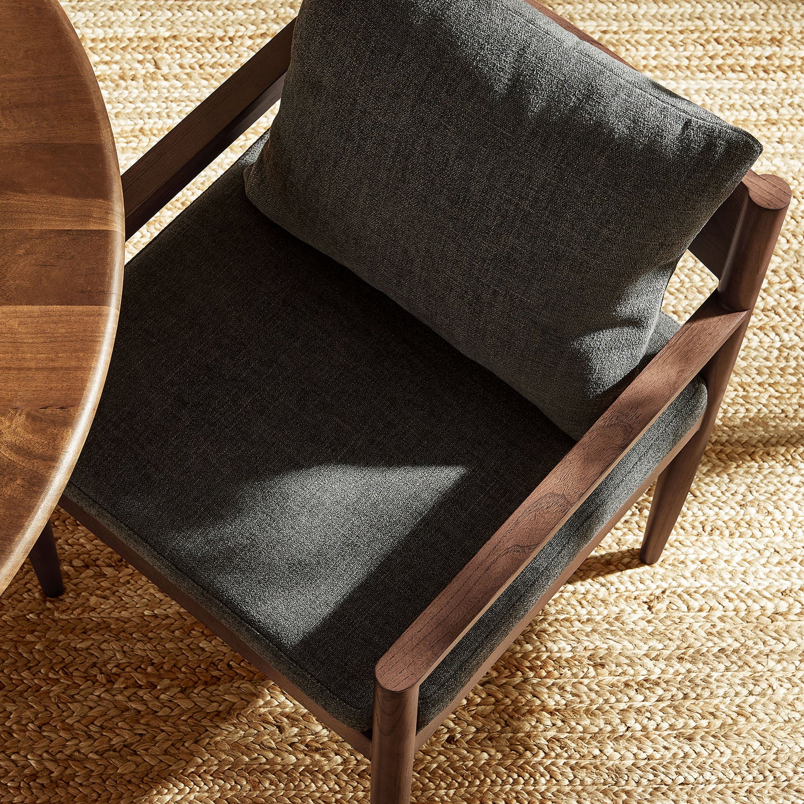Remington armchair beside a round dining table on a woven rug, showcasing plush charcoal cushions || EEI-7243-CHA || detail_room