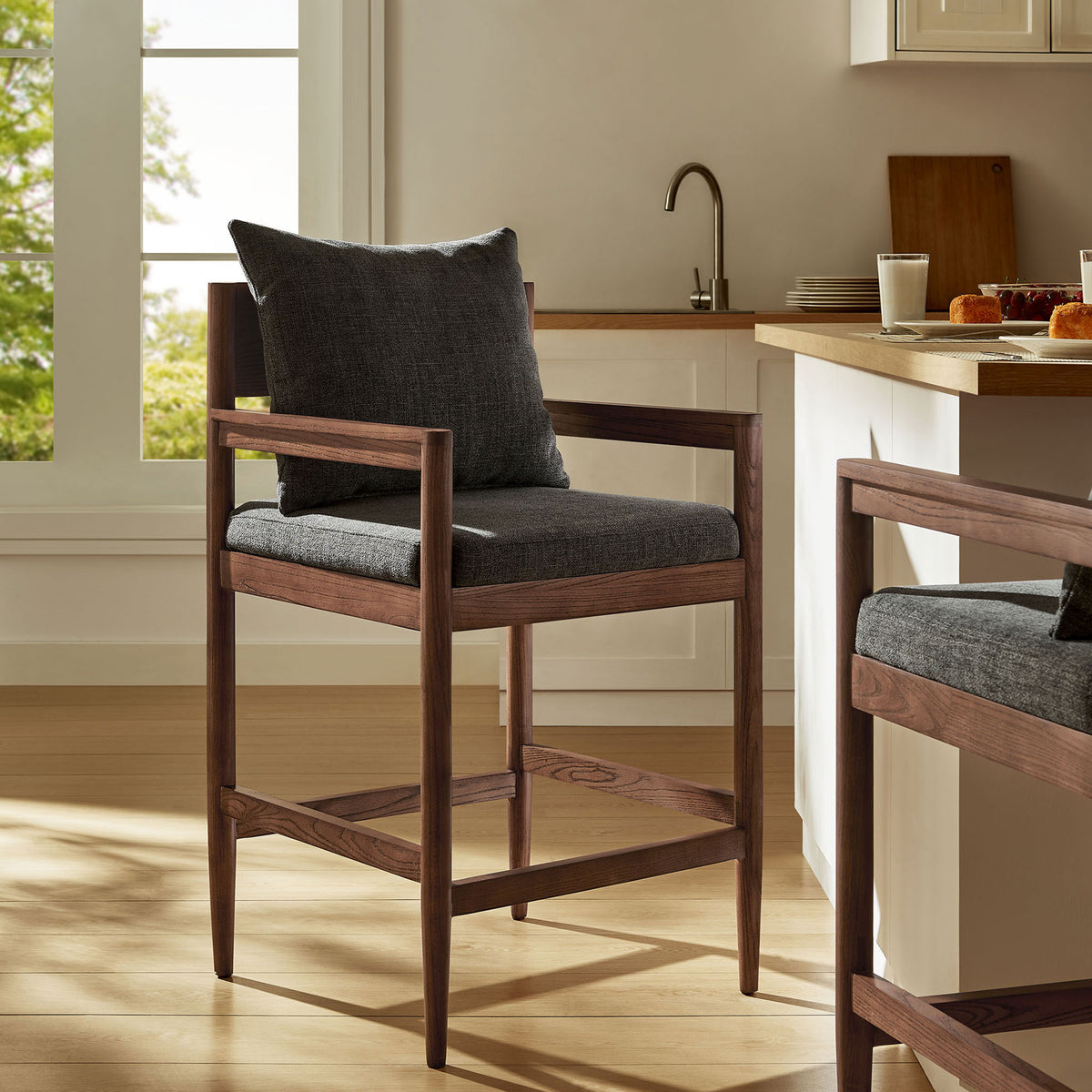 Rich wood tones and charcoal upholstery elevate a modern kitchen with cozy, understated style. || EEI-7244-CHA || front_angle_room