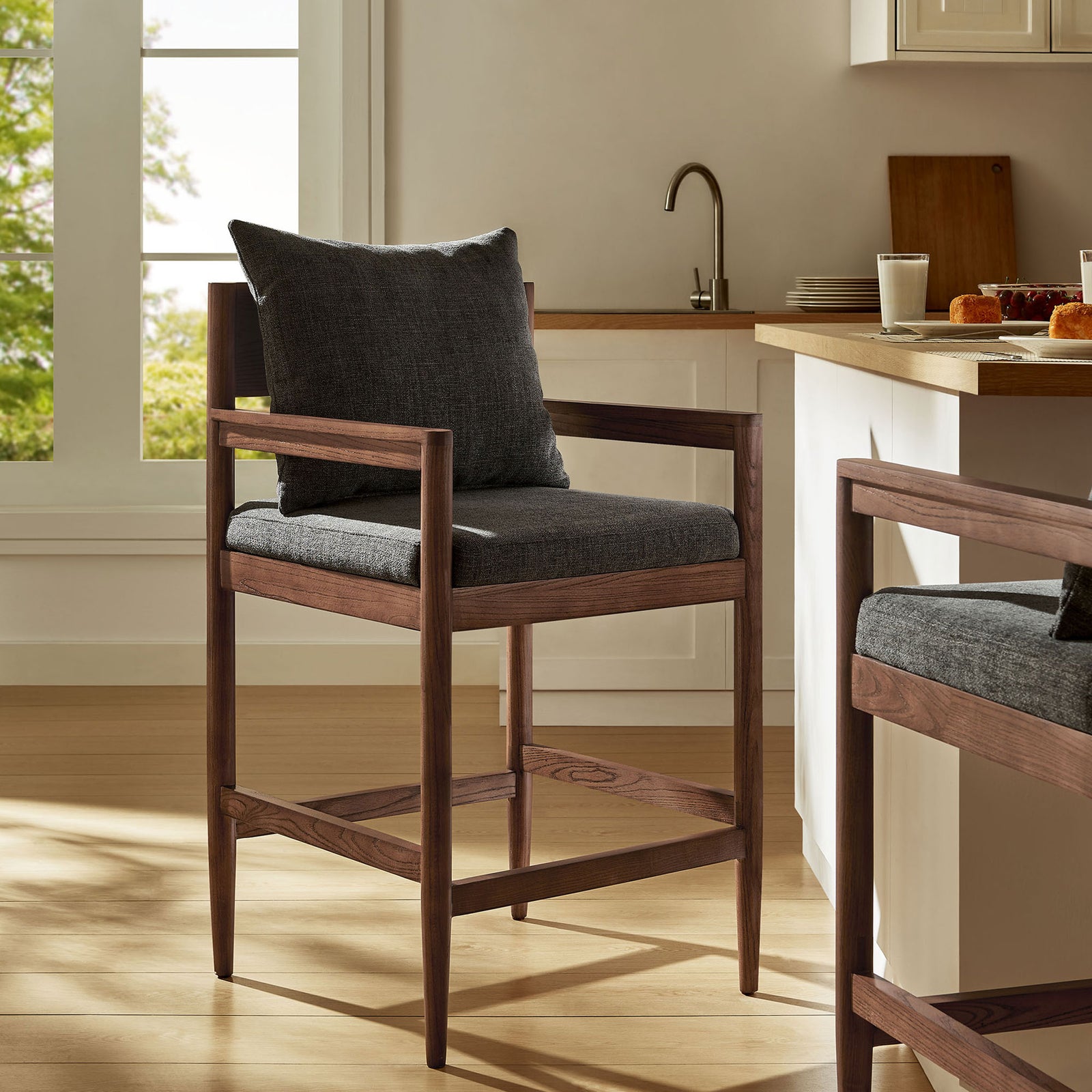 Rich wood tones and charcoal upholstery elevate a modern kitchen with cozy, understated style. || EEI-7244-CHA || front_angle_room