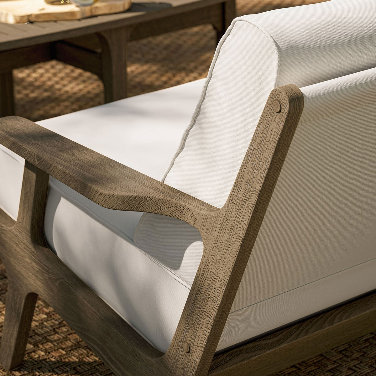 Saratoga loveseat on woven patio rug showcasing the warm teak frame and bright white cushions. || EEI-7247-WGR-WHI || detail_room