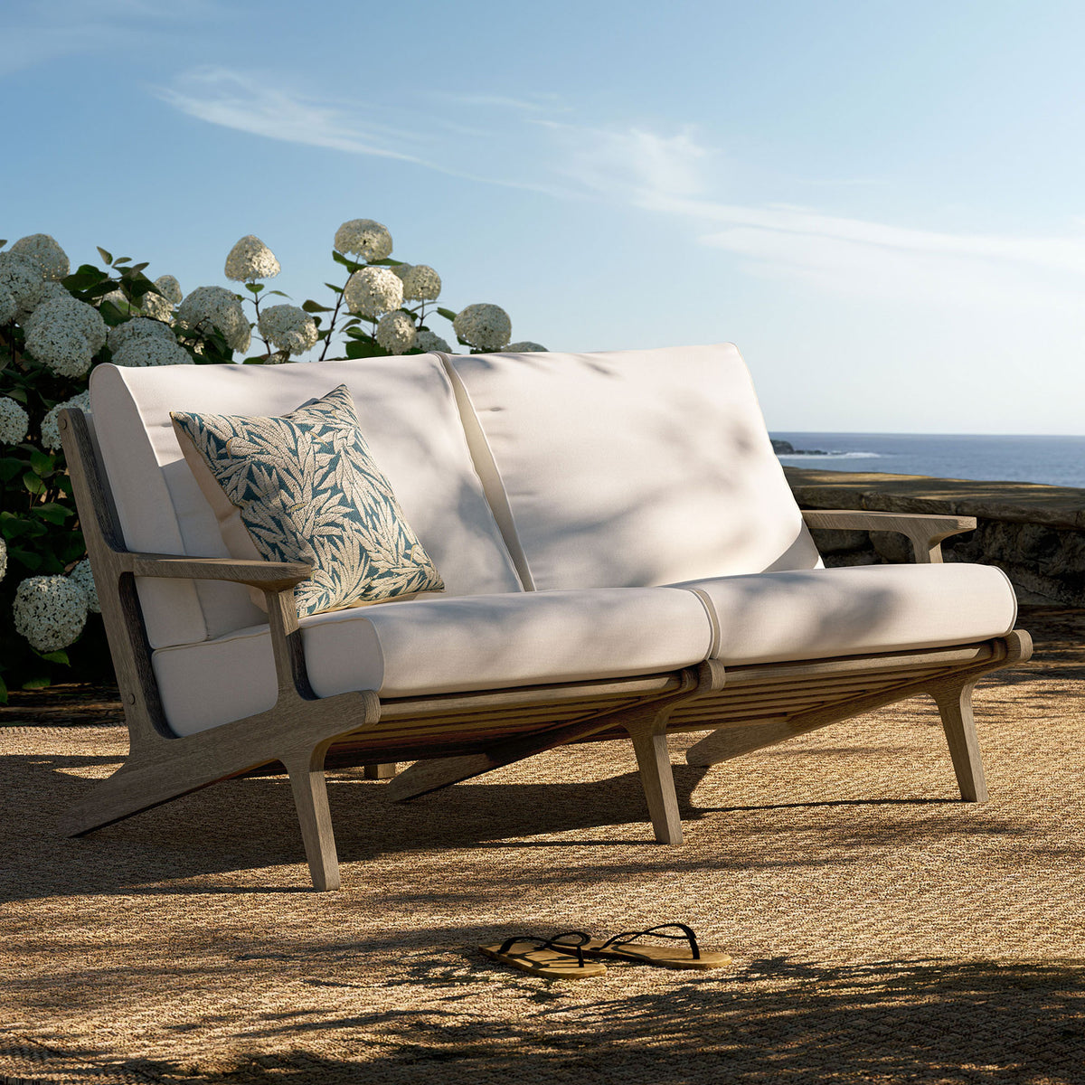 Saratoga teak loveseat arranged on a breezy coastal patio with plush white cushions and accent pillow. || EEI-7247-WGR-WHI || front_angle_room