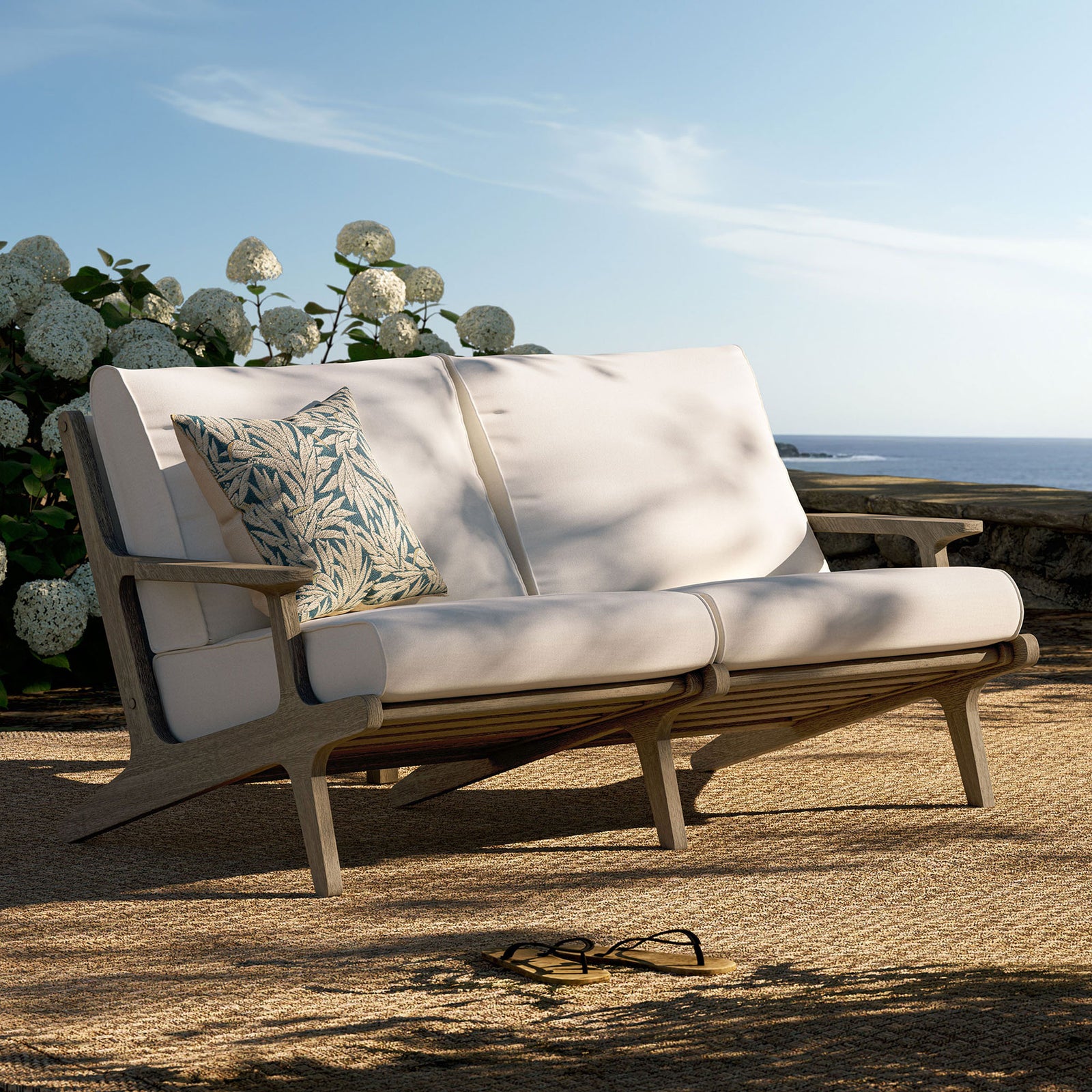 Saratoga teak loveseat arranged on a breezy coastal patio with plush white cushions and accent pillow. || EEI-7247-WGR-WHI || front_angle_room