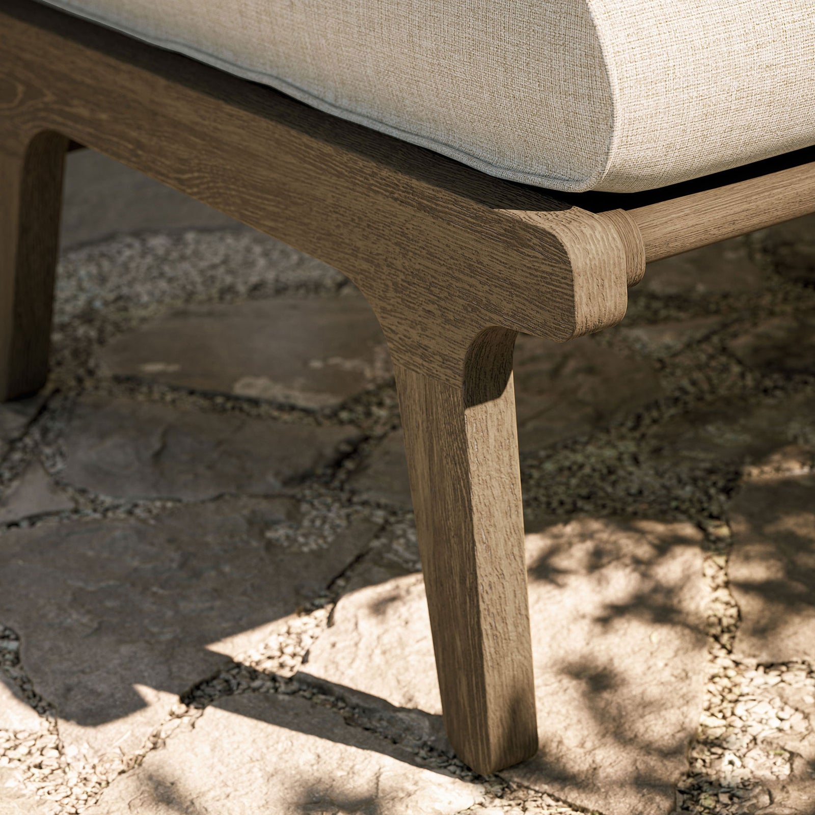 Weathered teak ottoman leg on stone patio, underscoring solid craftsmanship and outdoor strength || EEI-7250-WGR-PEB || leg_room