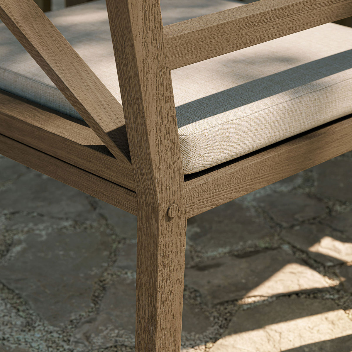Weathered teak frame and pebble cushion shown against stone pavers, echoing relaxed coastal style. || EEI-7253-WGR-PEB || leg_room
