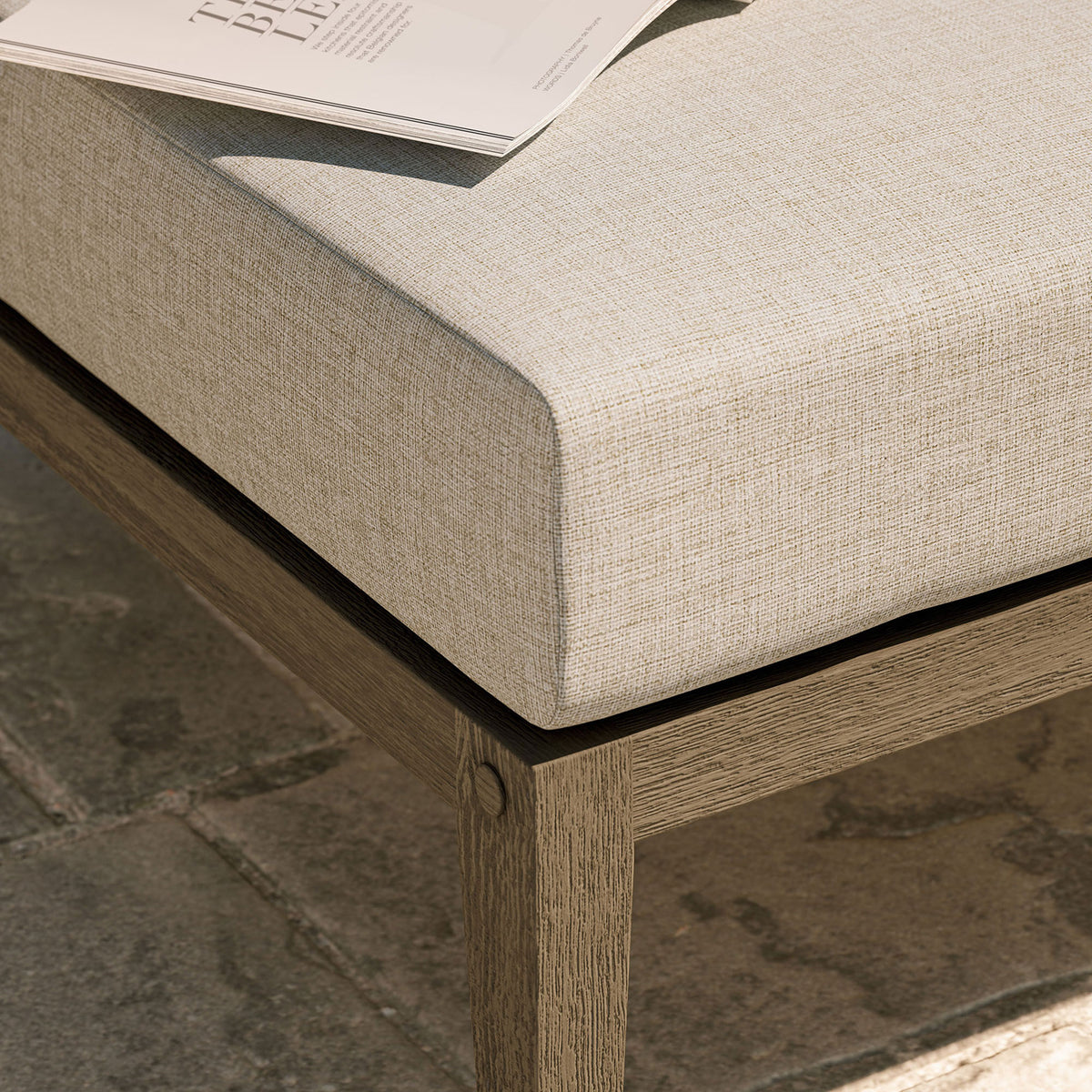 Textured beige cushion and teak base bring relaxed comfort to an outdoor stone patio setting || EEI-7255-WGR-PEB || detail_room