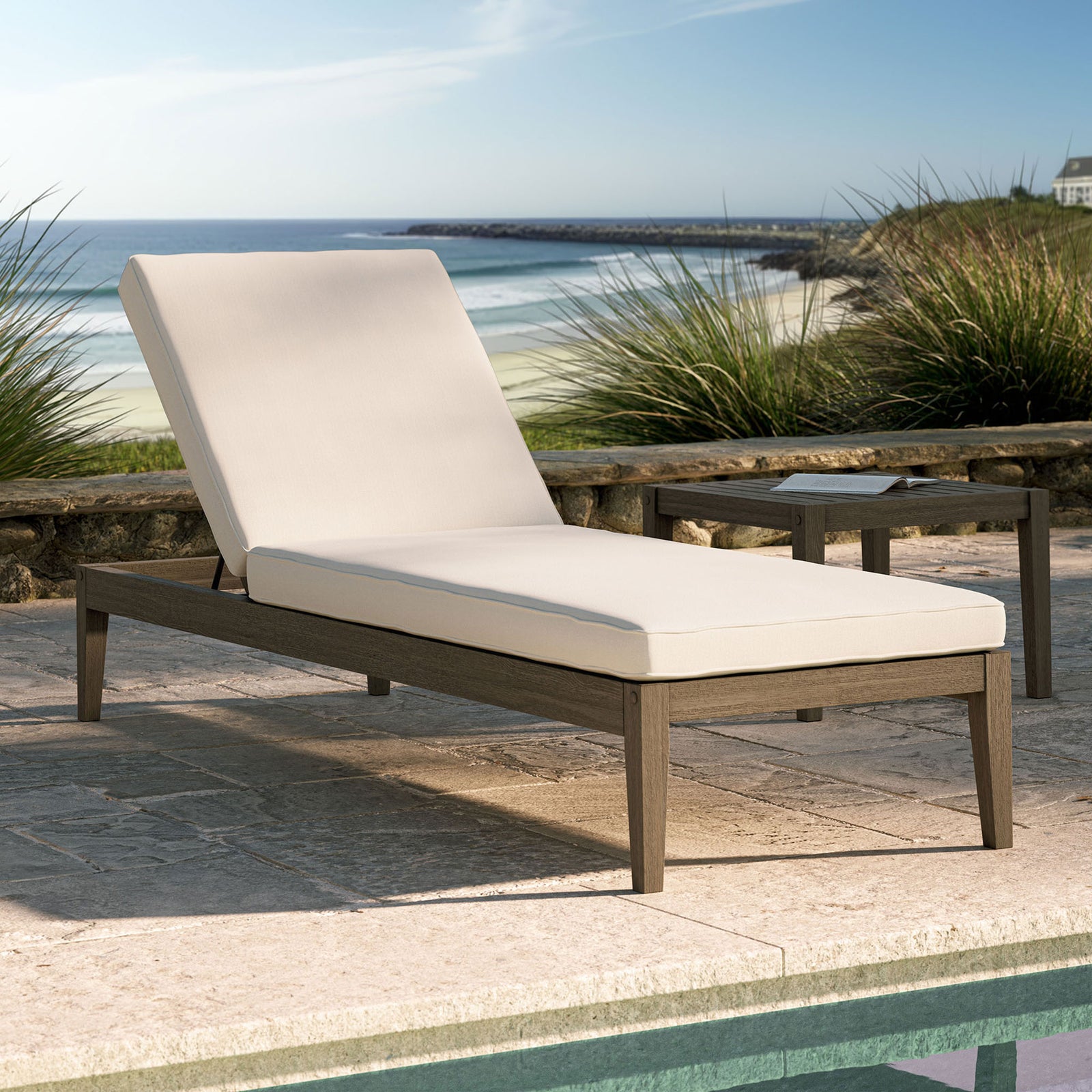 Outdoor teak chaise lounge with white cushion styled by a pool with a serene coastal backdrop || EEI-7256-WGR-WHI || front_angle_converted_room