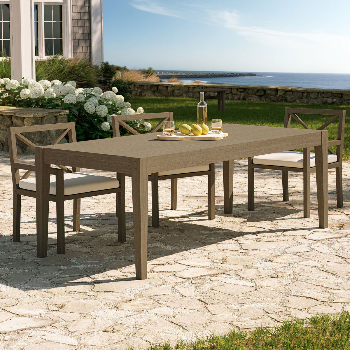 Weathered gray teak outdoor dining table on a stone patio, paired with chairs for relaxed alfresco meals || EEI-7257-WGR || front_angle_room