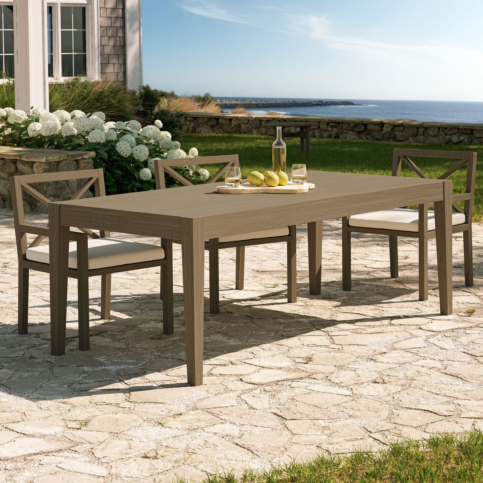 Weathered gray teak outdoor dining table on a stone patio, paired with chairs for relaxed alfresco meals || EEI-7257-WGR || front_angle_room