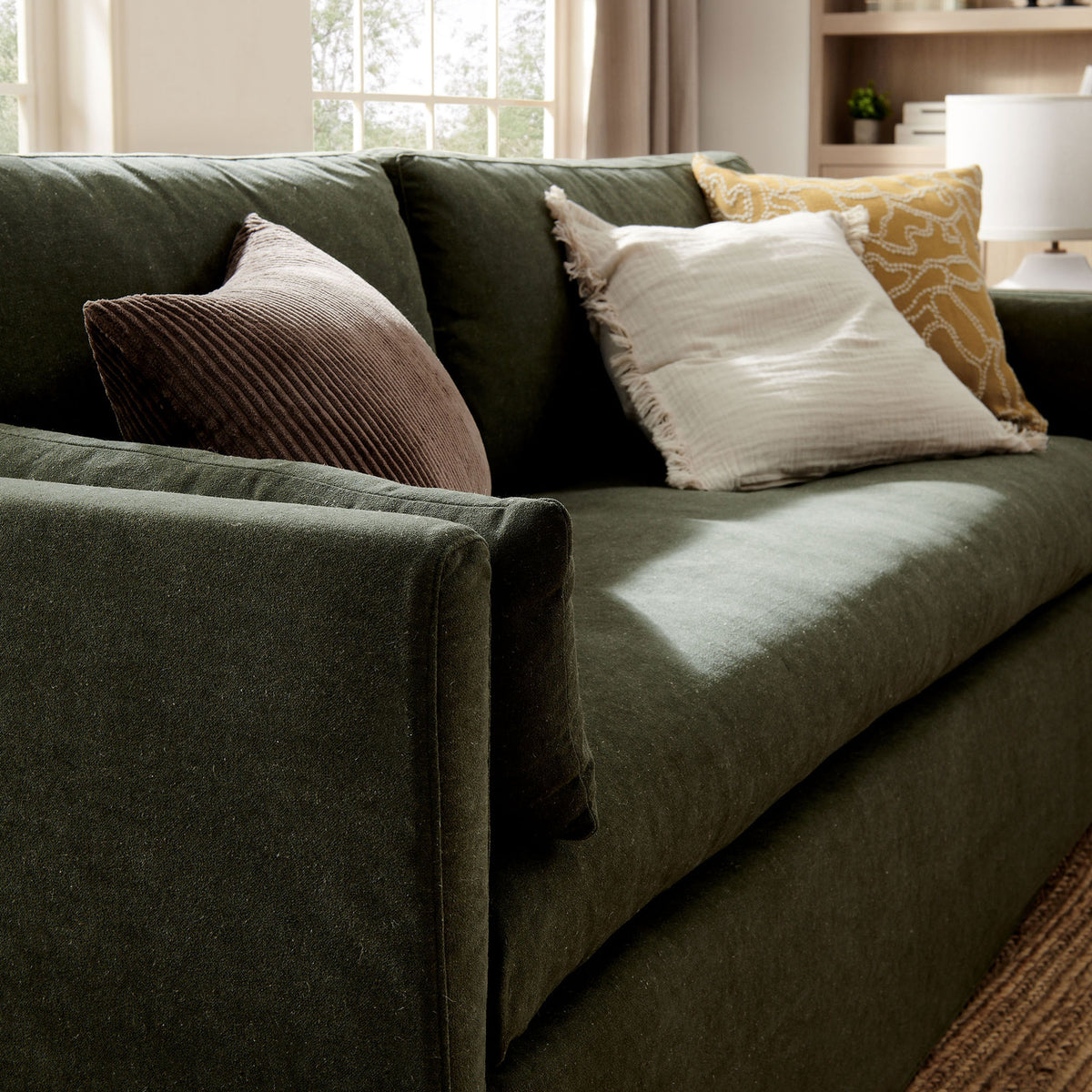 Sage green sofa styled with layered accent pillows, emphasizing the plush bench cushion in a bright room || EEI-7260-SGE || detail_room