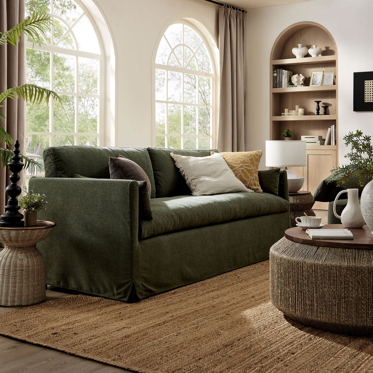 Sage green slipcovered sofa in a sunlit living room with natural wood accents and woven textures || EEI-7260-SGE || front_angle_room