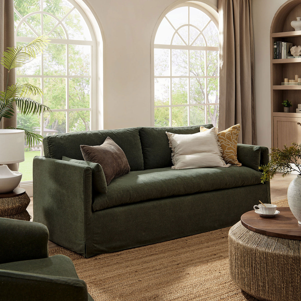 Sage green sofa arranged in an airy living space with large arched windows and neutral decor || EEI-7260-SGE || front_angle_room