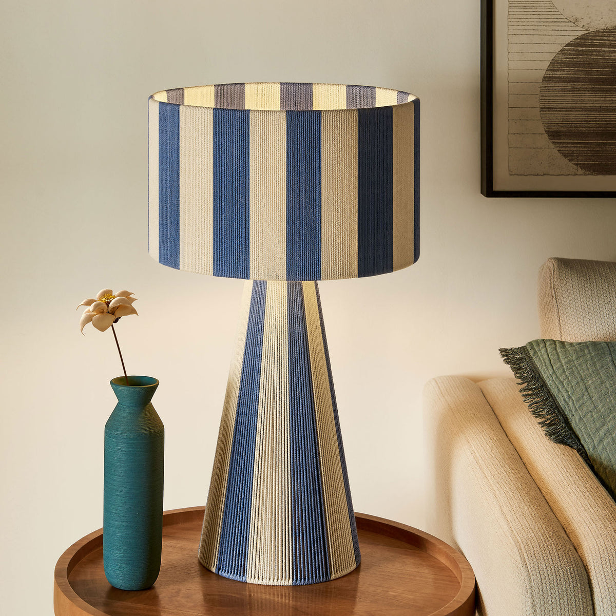 Glowing capri blue striped table lamp brings warm ambient light beside an inviting sofa. || EEI-7261-CBL || front_on_room