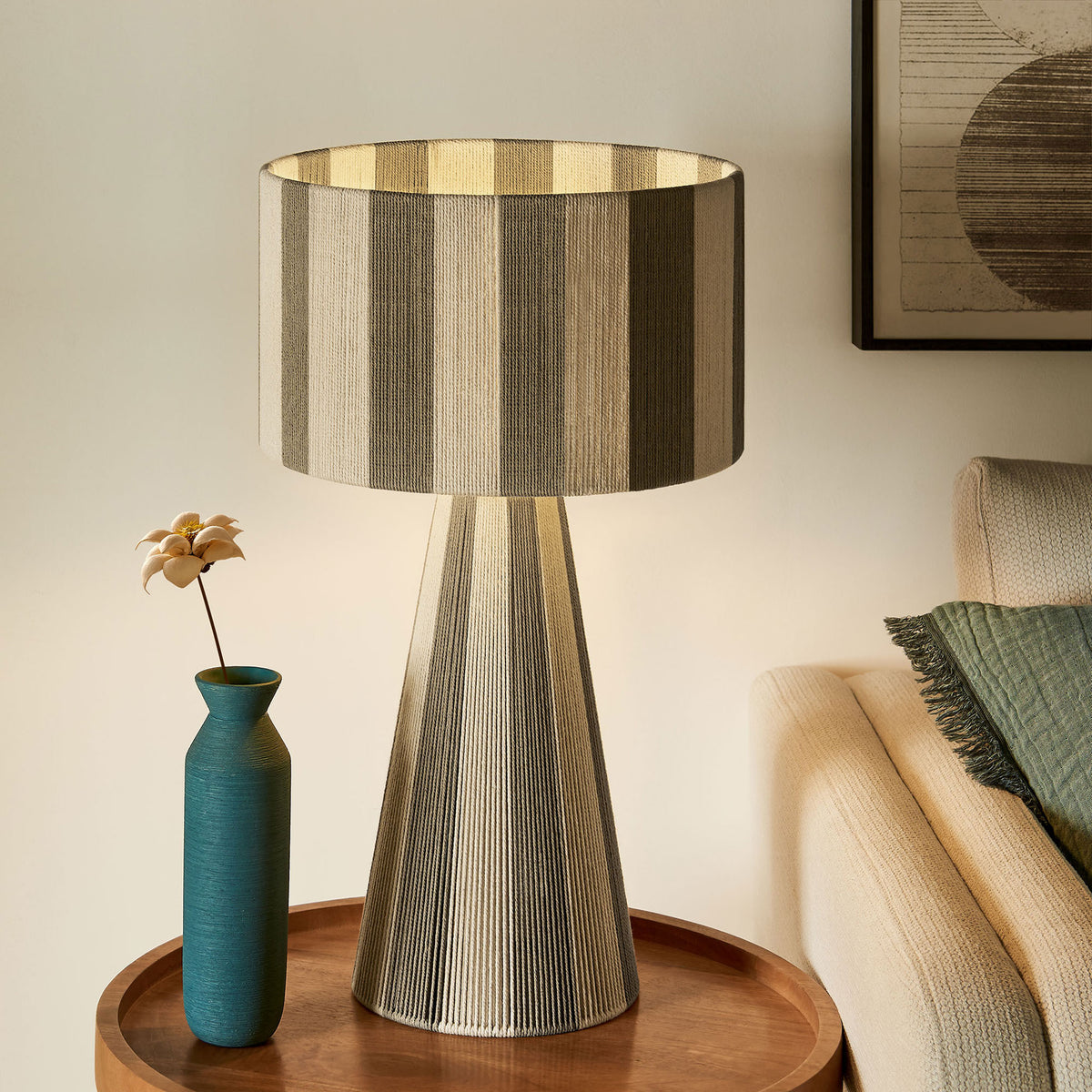 Illuminated cobblestone striped table lamp creates a cozy glow beside a modern sofa. || EEI-7261-COB || front_on_room