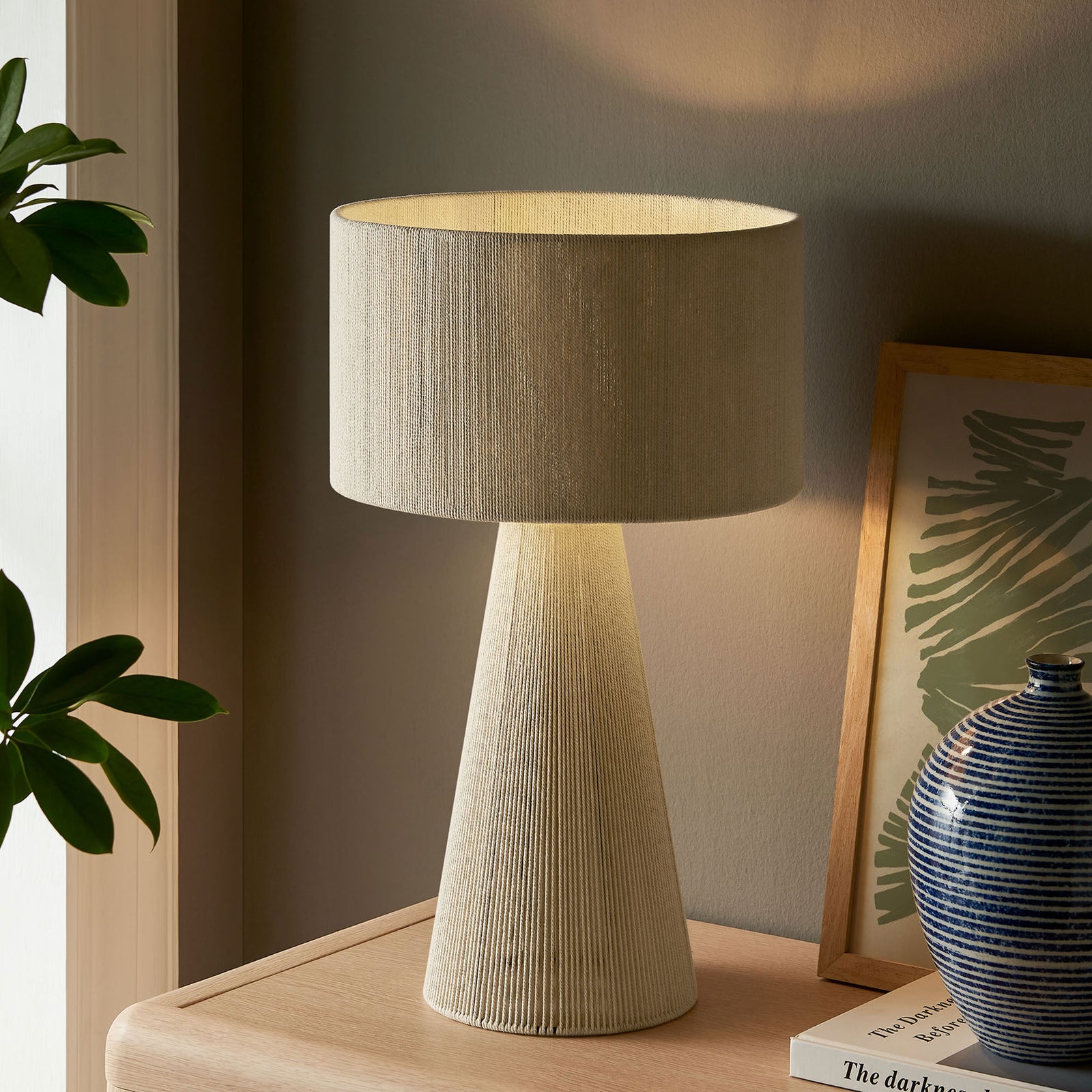 Natural cotton table lamp softly glowing to create a cozy, relaxed ambiance. || EEI-7262-NAT || front_angle_on_room