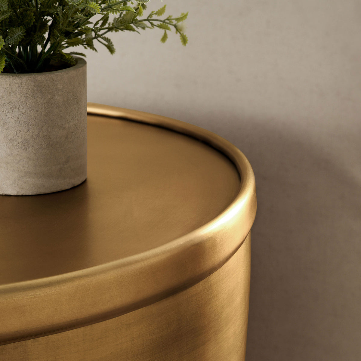 Viora burnished brass side table styled with greenery, adding warm metallic shine beside a sofa. || EEI-7272-BBR || detail_room