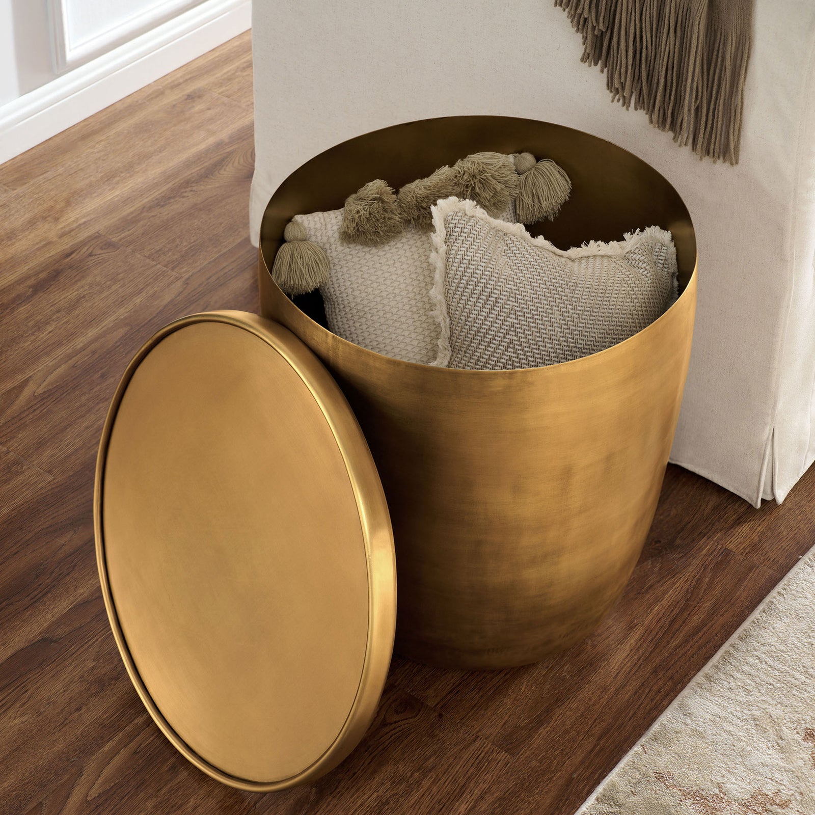 Burnished brass storage side table opened to hold throw pillows, bringing hidden storage to the living room. || EEI-7272-BBR || front_angle_open_room
