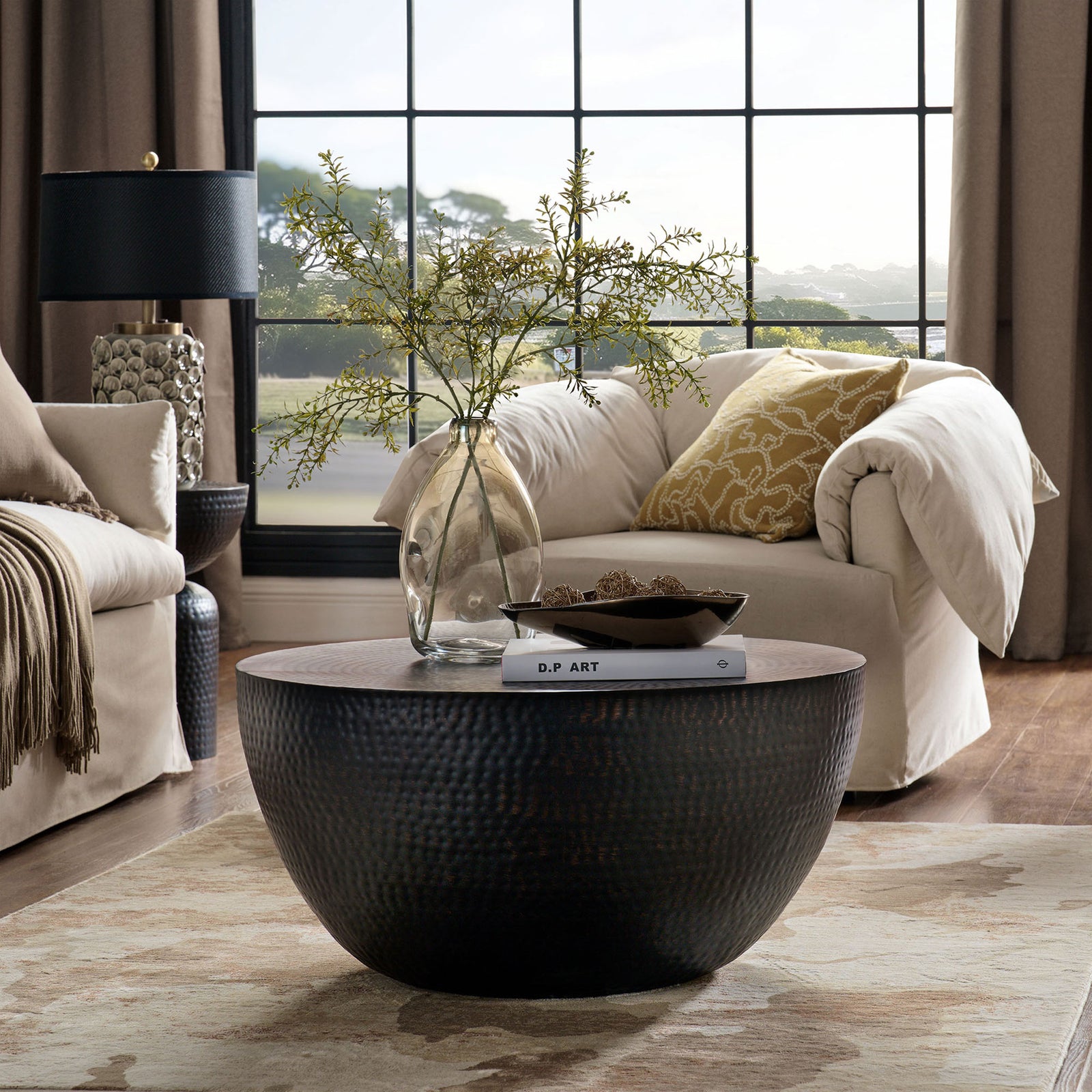 Statement drum coffee table in hammered metal adds sculptural presence to modern living spaces || EEI-7279-BLK || front_angle_room