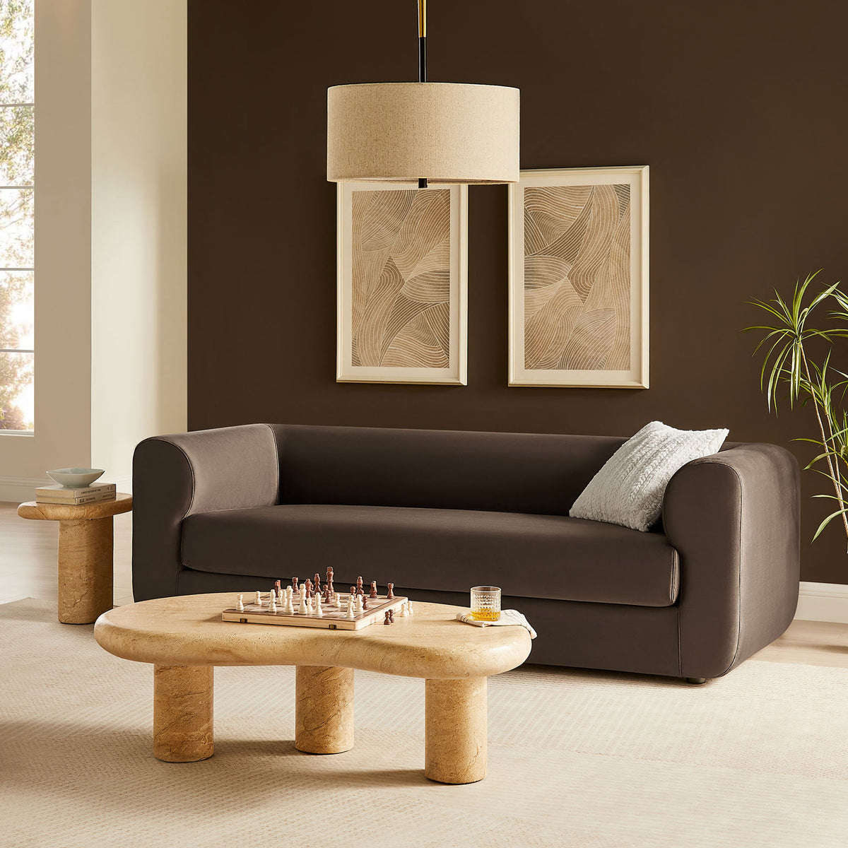 Chocolate brown velvet sofa styled in a warm modern living room with sculptural stone tables and wall art || EEI-7281-CHB || front_angle_room