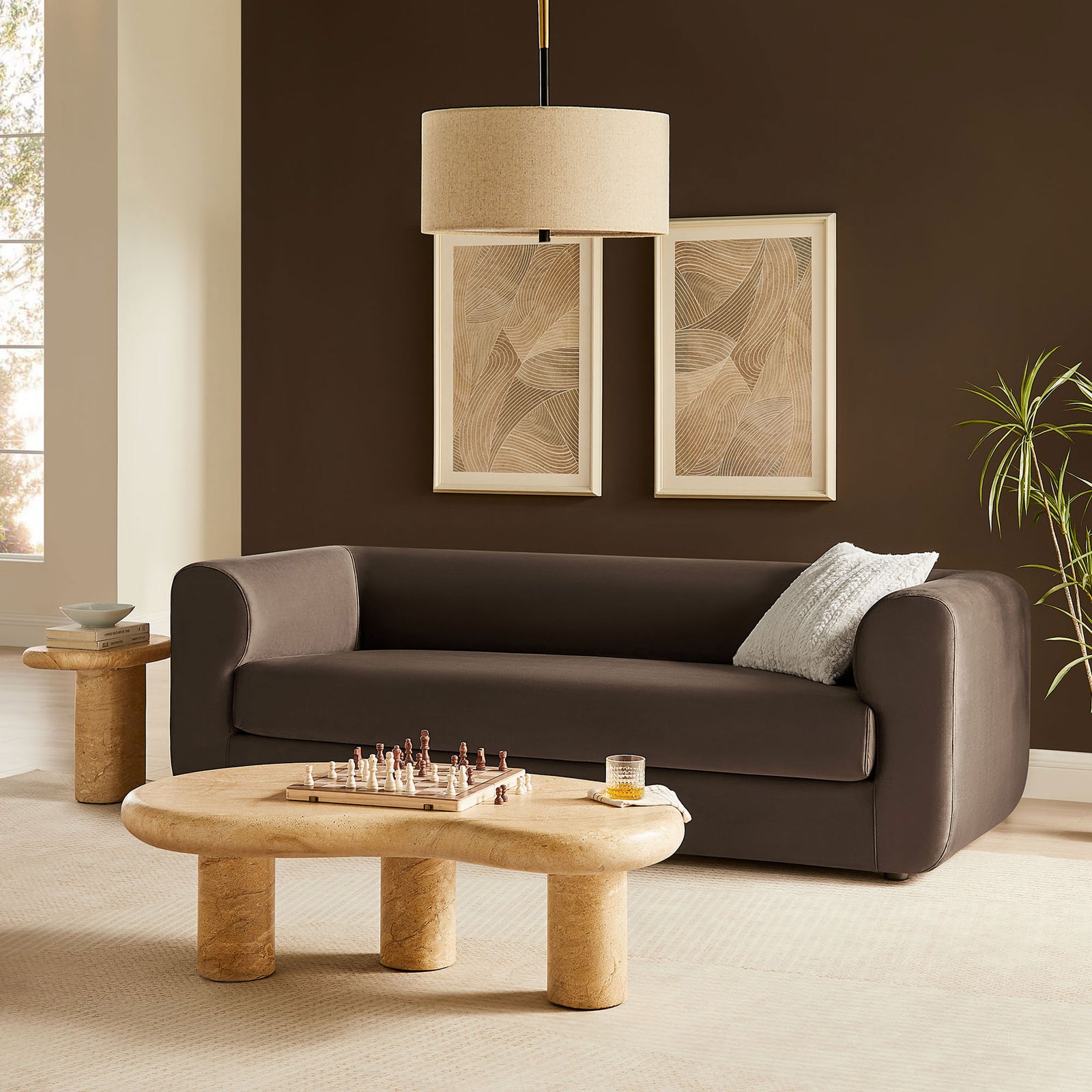 Chocolate brown velvet sofa styled in a warm modern living room with sculptural stone tables and wall art || EEI-7281-CHB || front_angle_room