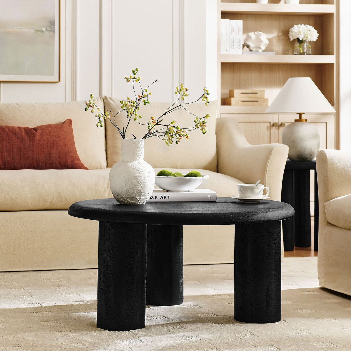 Modern round coffee table anchors the seating area with sculptural three-leg design || EEI-7286-BLK || front_angle_room