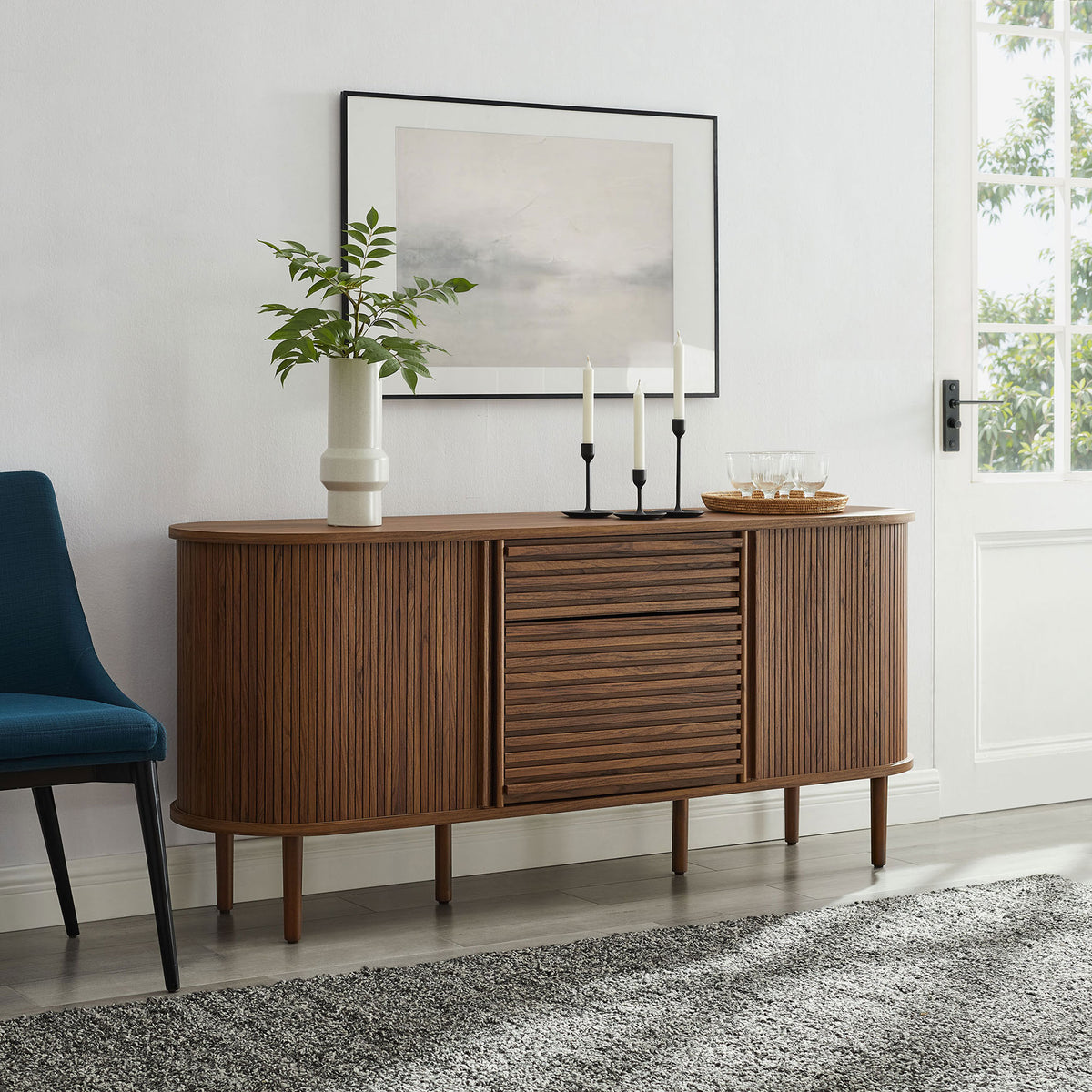 Oval walnut sideboard anchors a modern living room, pairing fluted doors with minimalist decor and soft textures || EEI-7293-WAL || front_angle_room