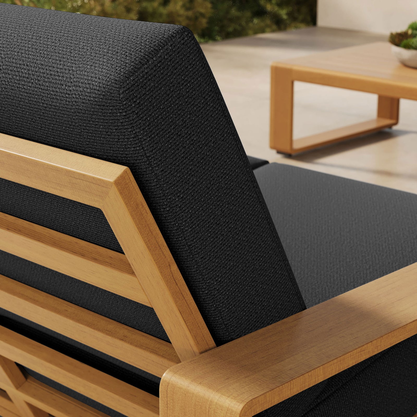 Rich charcoal cushion and faux wood frame detail stand out against the light stone terrace || EEI-7297-CHA-NAT || detail_room