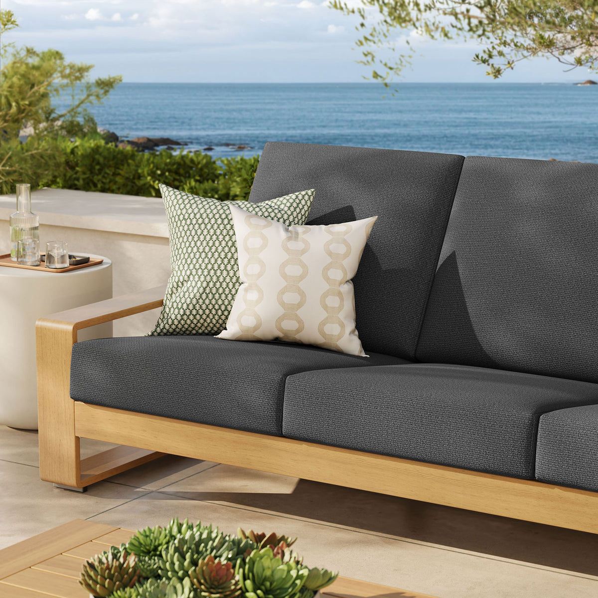 Charcoal outdoor sofa with natural frame styled with pillows, adding cozy contrast to a sunlit terrace || EEI-7298-CHA-NAT || detail_room
