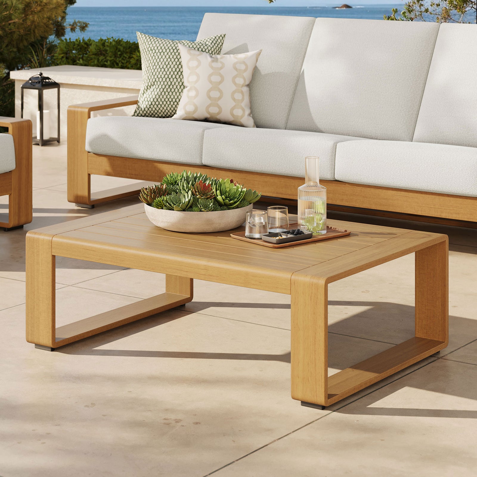Natural faux wood coffee table paired with coordinating outdoor seating on a coastal patio || EEI-7299-NAT || front_angle_room