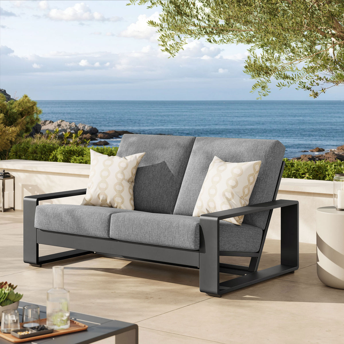 Light gray cushions and charcoal frame anchor an inviting outdoor lounge vignette by the sea || EEI-7301-LGR-GRY || front_angle_room