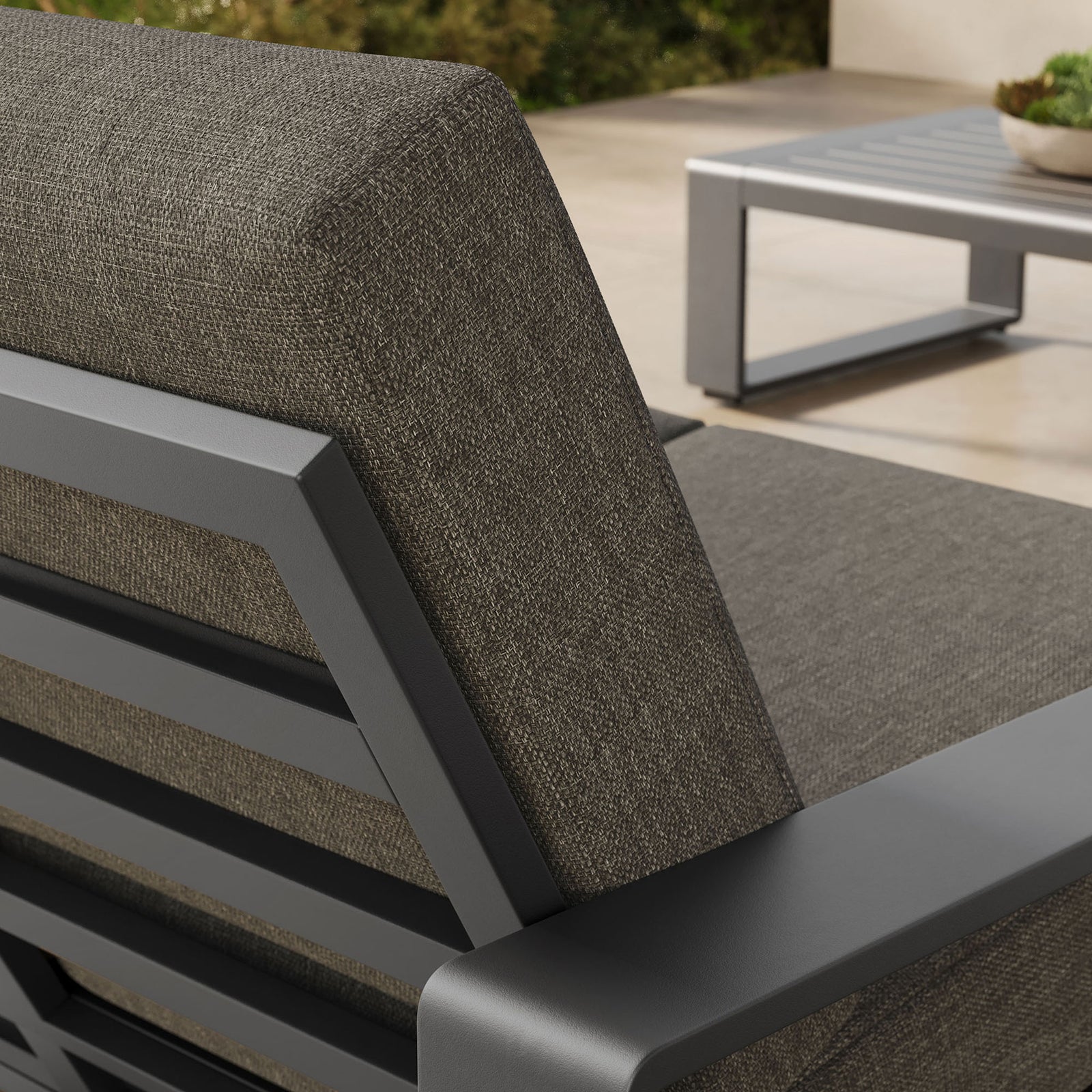 Textured smoke gray cushion and sleek frame stand out against the warm stone patio backdrop || EEI-7301-SMO-GRY || detail_room