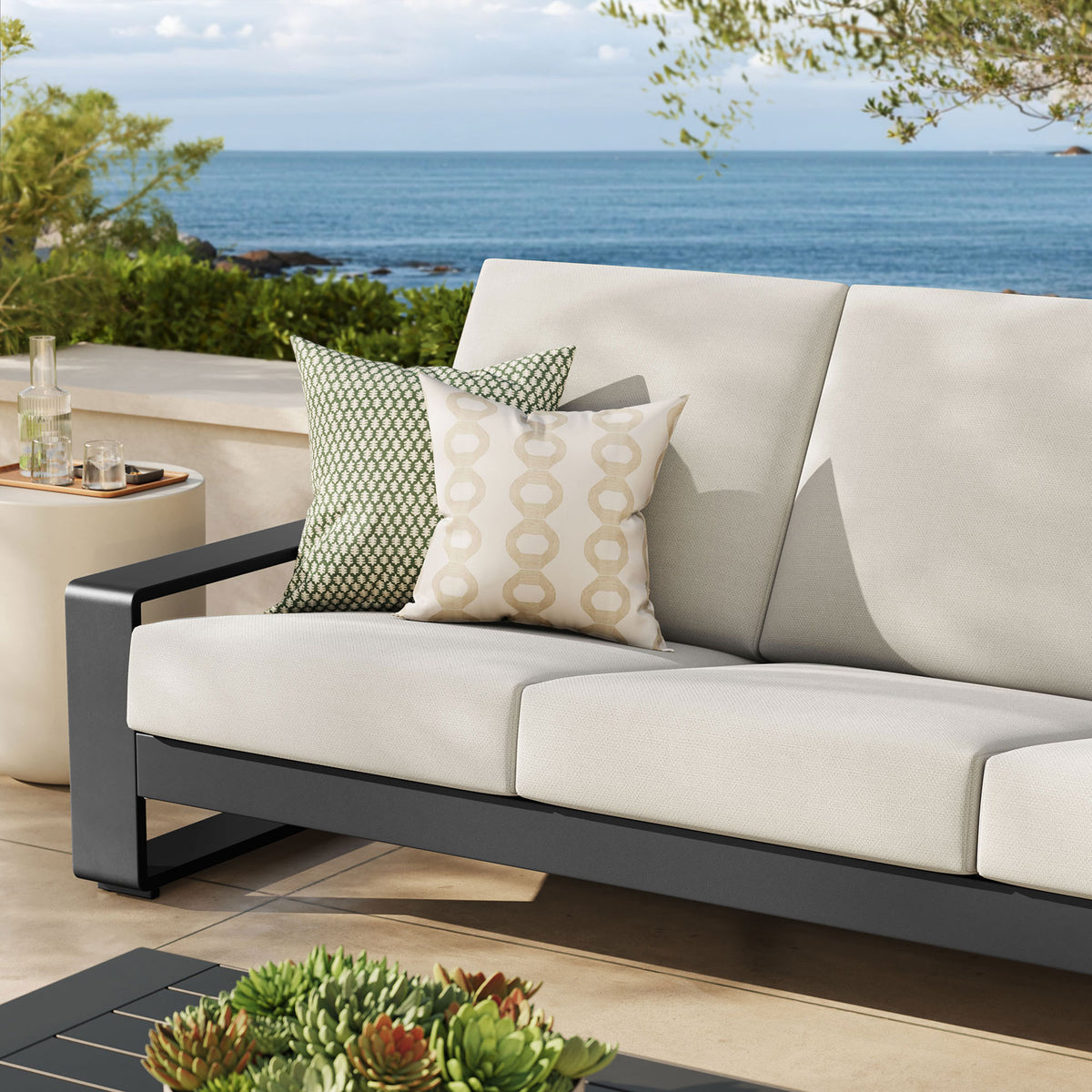 Cream outdoor sofa styled with patterned pillows, adding soft contrast against the dark aluminum base || EEI-7302-CRE-GRY || detail_room