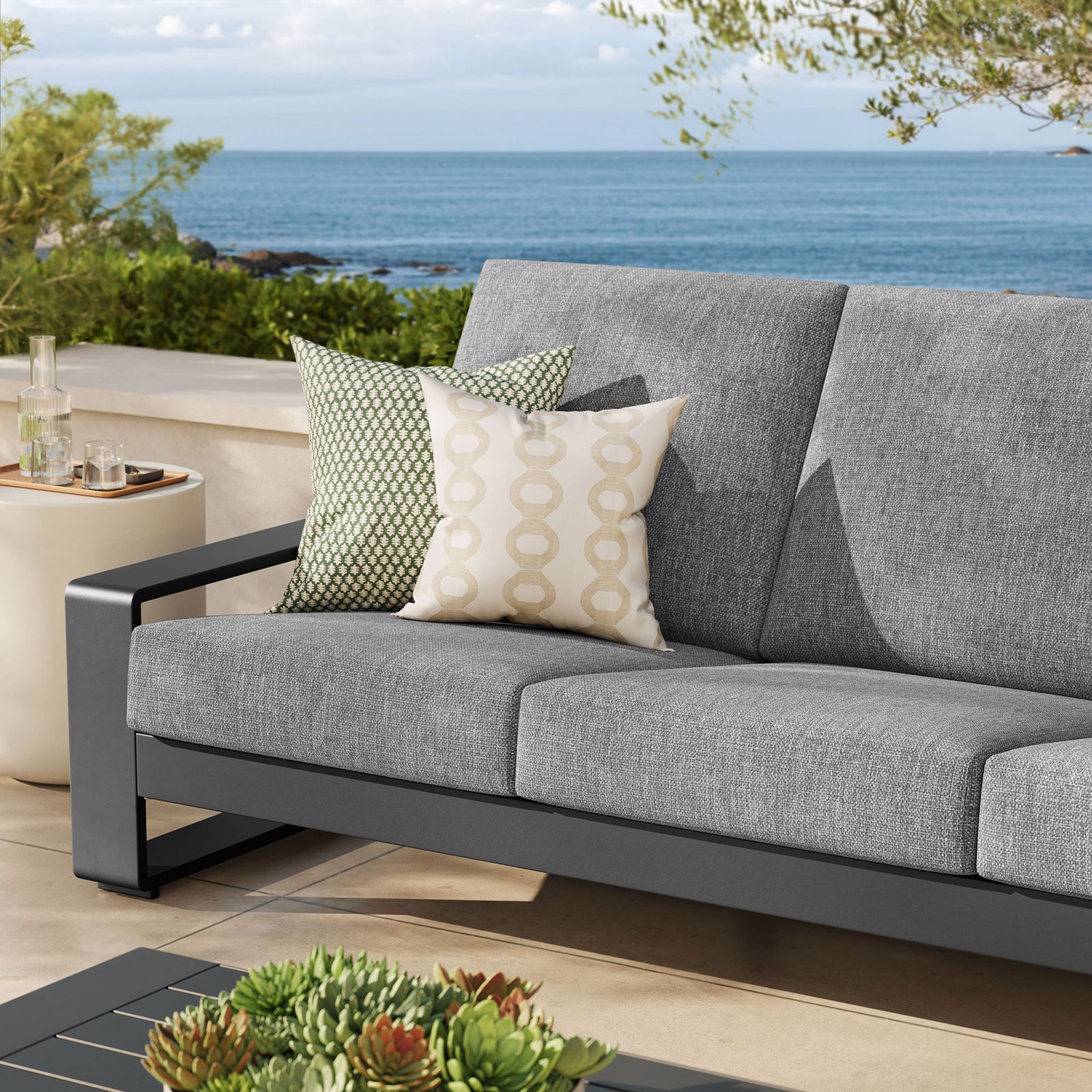 Light gray outdoor sofa dressed with accent pillows, creating a soft neutral look on a sunny patio || EEI-7302-LGR-GRY || detail_room