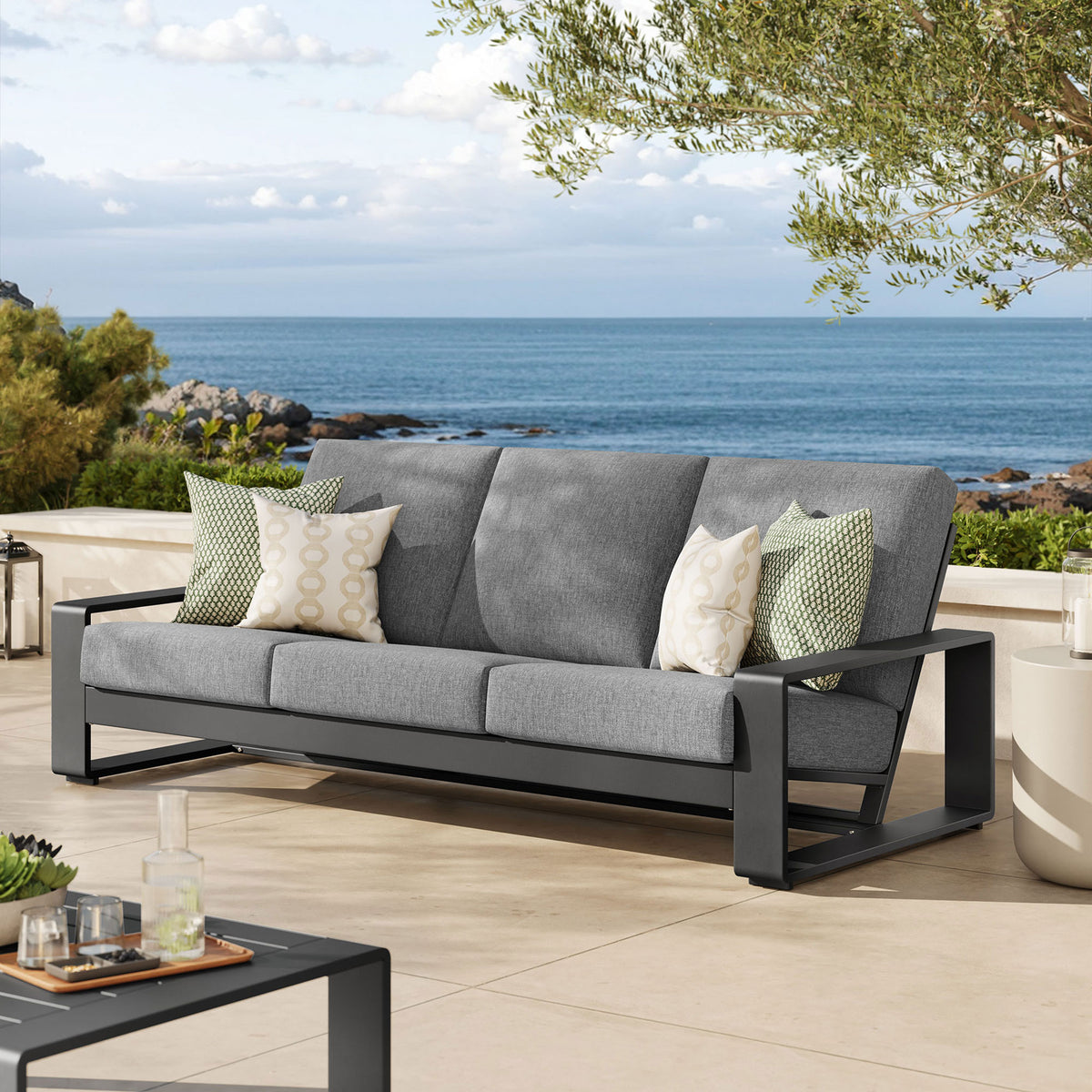 Light gray three-seat outdoor sofa on a coastal terrace, combining plush comfort with clean modern lines || EEI-7302-LGR-GRY || front_angle_room
