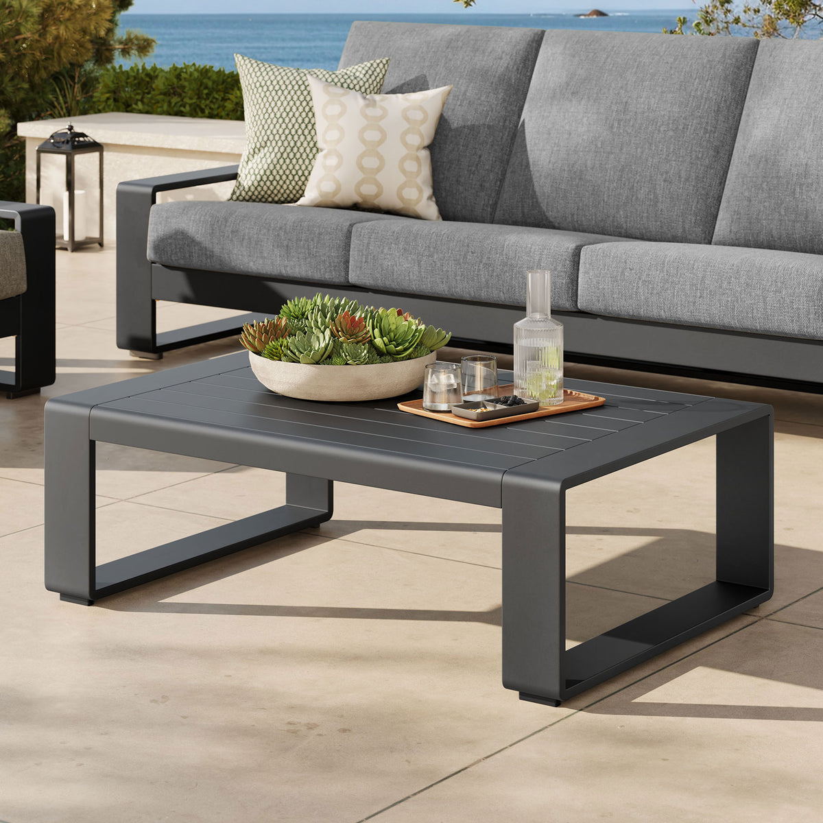 Gray aluminum coffee table paired with matching outdoor sofa on a coastal patio || EEI-7303-GRY || front_angle_room
