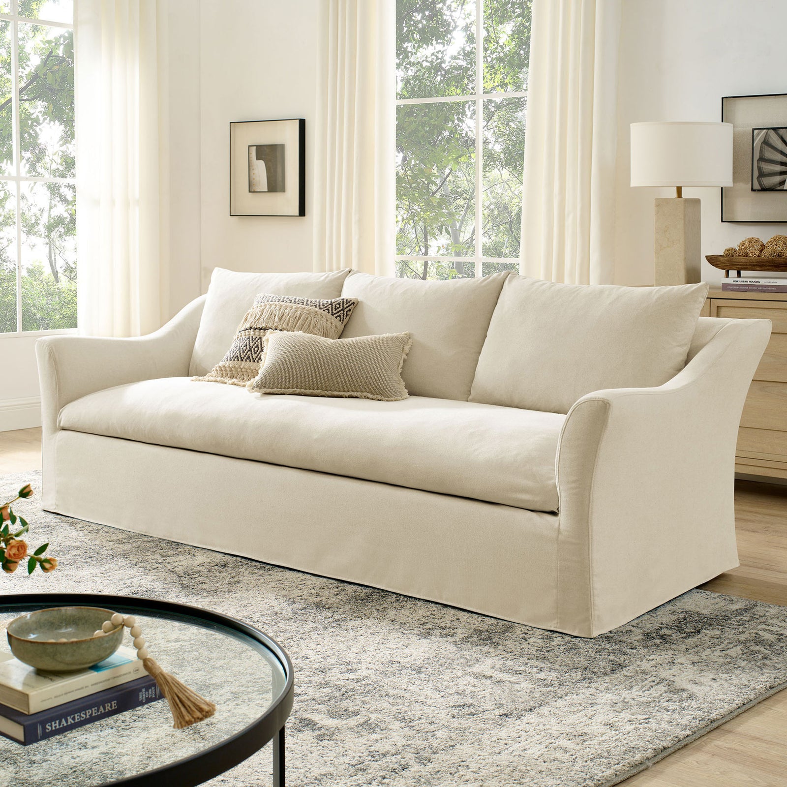 Slipcovered linen blend sofa anchoring a cozy living space with modern decor, rug, and round glass coffee table || EEI-7310-LIN || front_angle_room