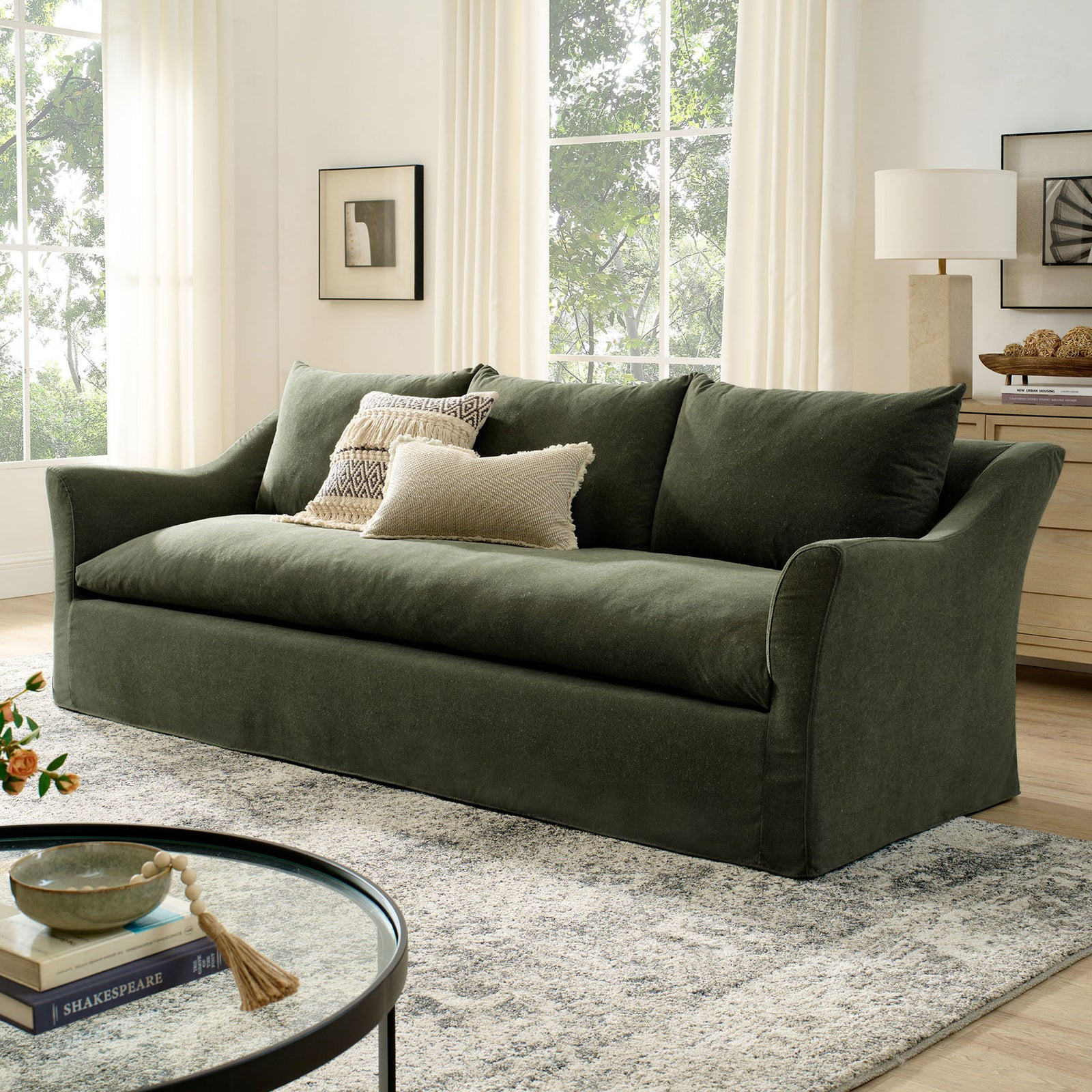 Sage slipcovered sofa anchors a bright living room with plush cushions and a long bench seat on a patterned rug || EEI-7310-SGE || front_angle_room