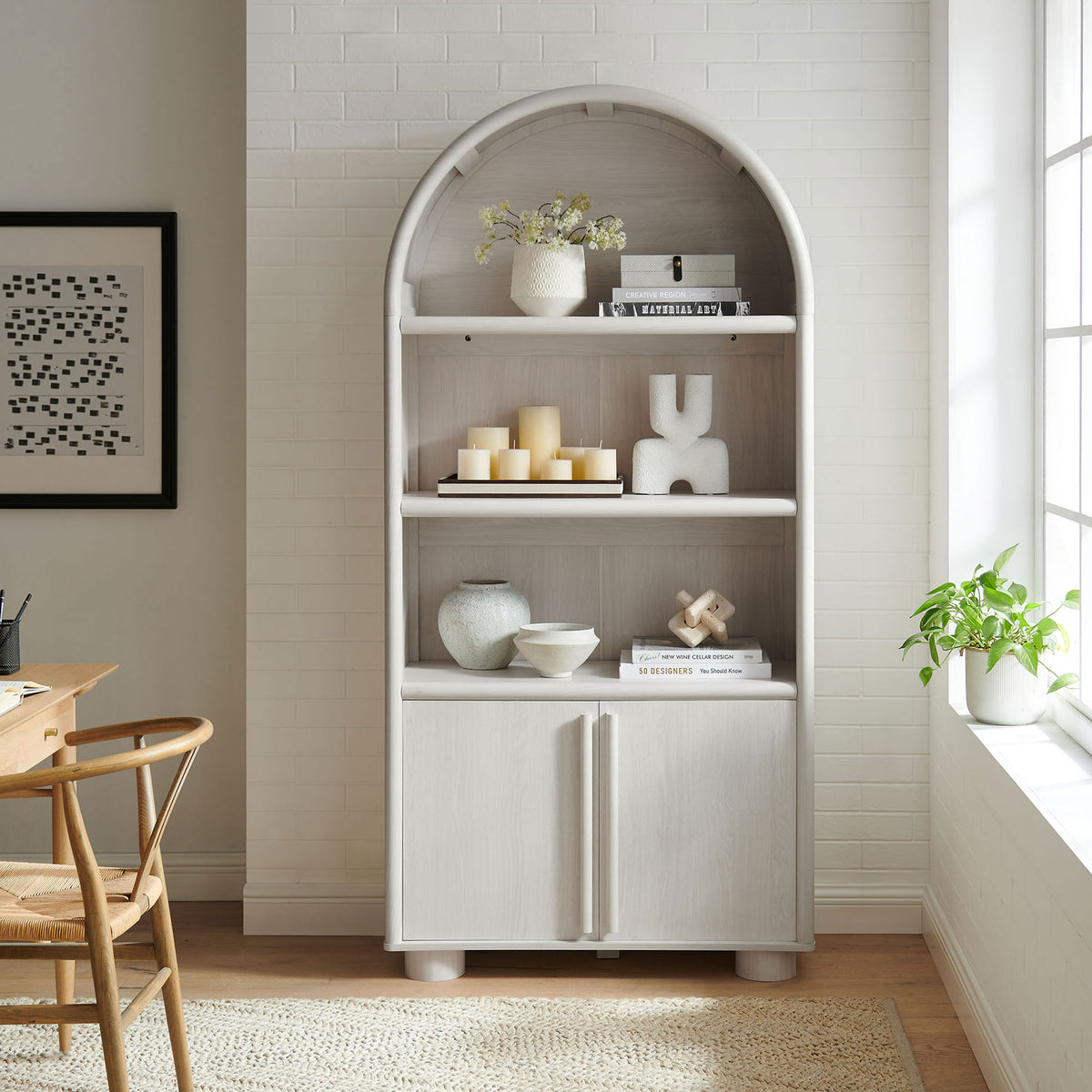 Tall arched bookcase styled with decor, featuring wood grain shelves and a clean two-door base || EEI-7314-ASH || front_room