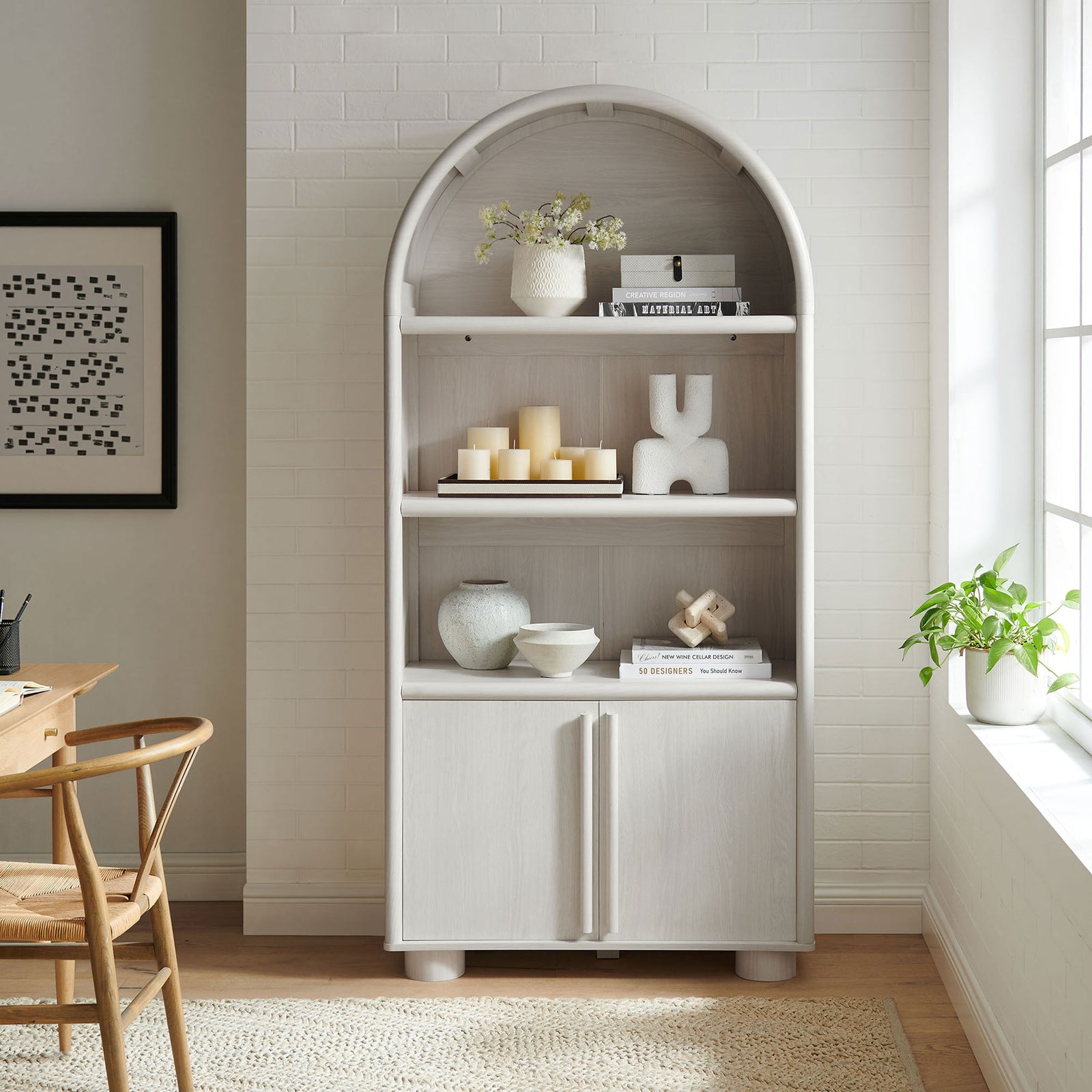 Tall arched bookcase styled with decor, featuring wood grain shelves and a clean two-door base || EEI-7314-ASH || front_room