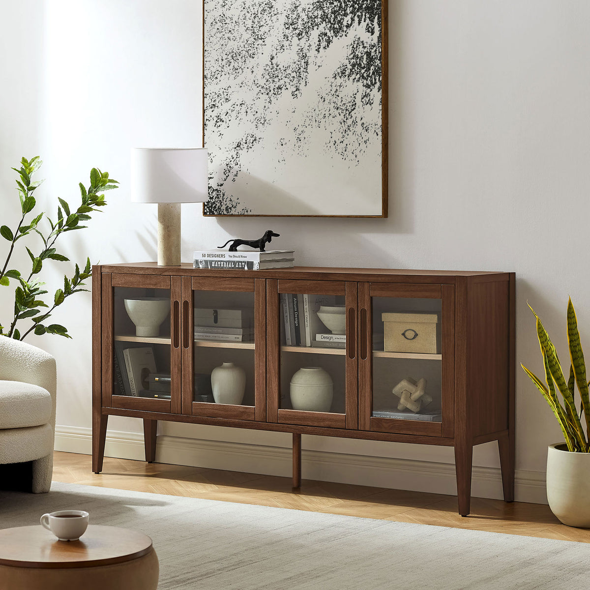 Walnut sideboard styled in a bright living room, showcasing its glass doors and slim tapered legs || EEI-7319-WAL-ASH || front_angle_room