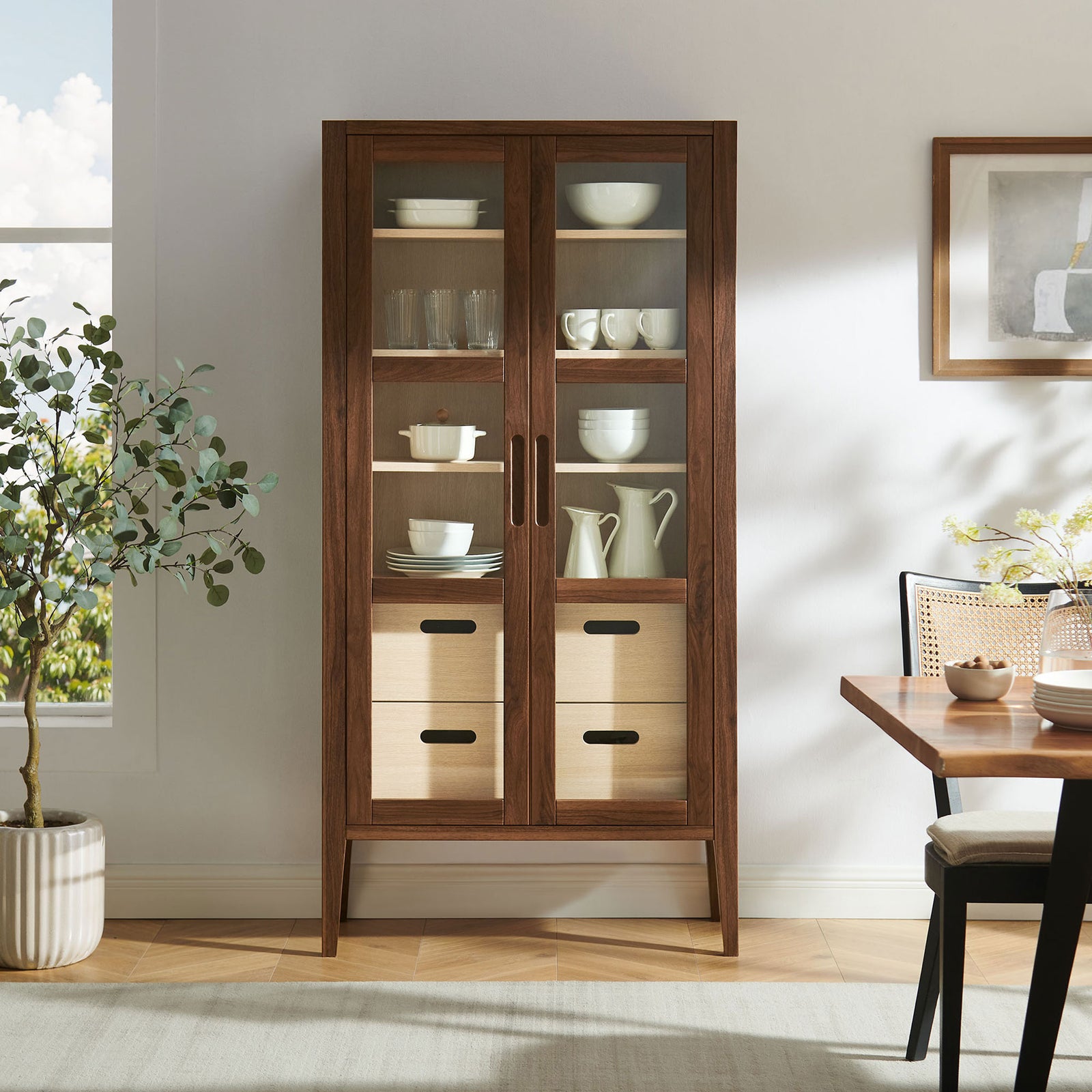 Walnut Nell display cabinet styled in a dining room, showcasing dishes and decor behind glass doors and drawers || EEI-7320-WAL-ASH || front_room