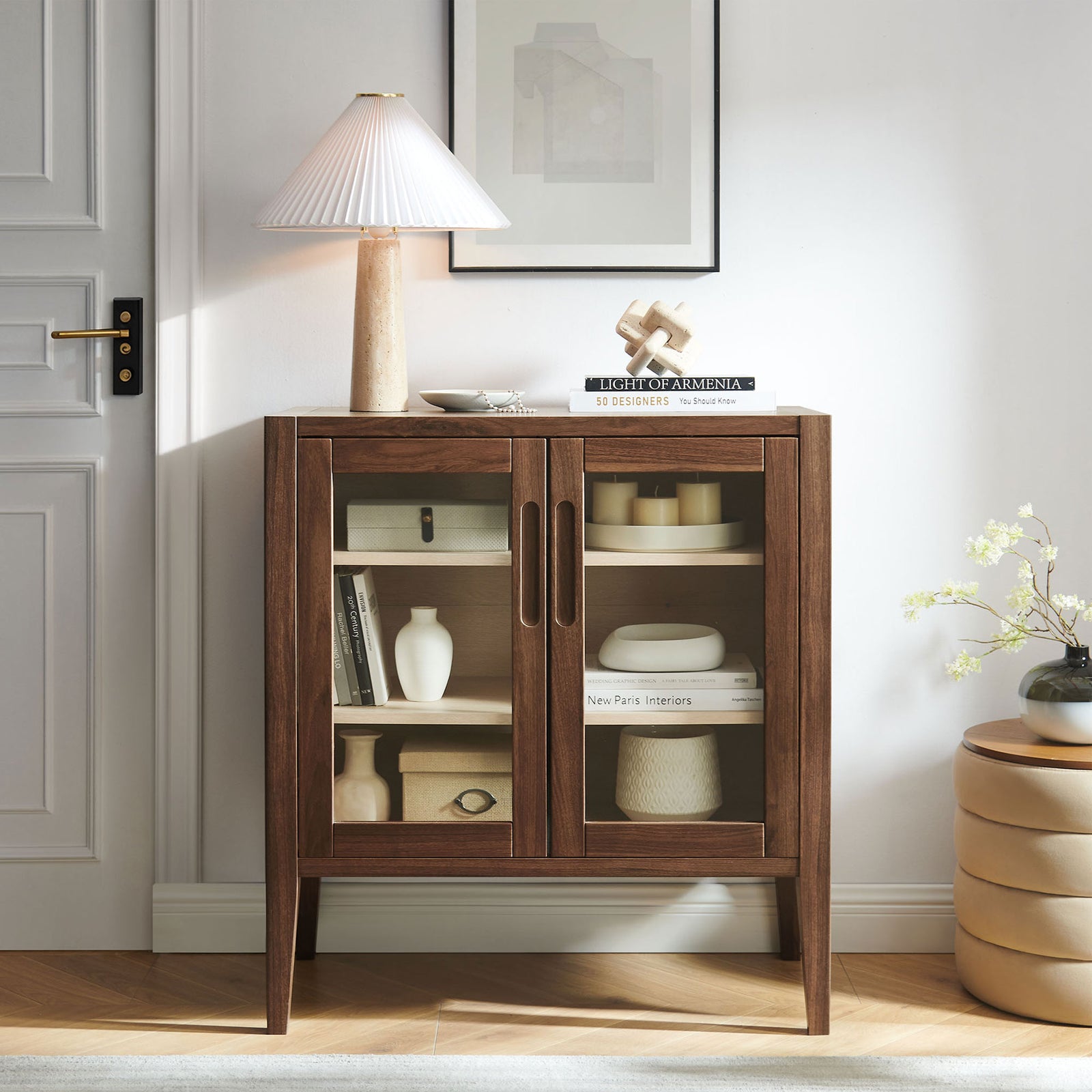 Walnut Nell accent cabinet styled in a modern living space with decor accents, offering elegant glass-front storage || EEI-7321-WAL-ASH || front_angle_room