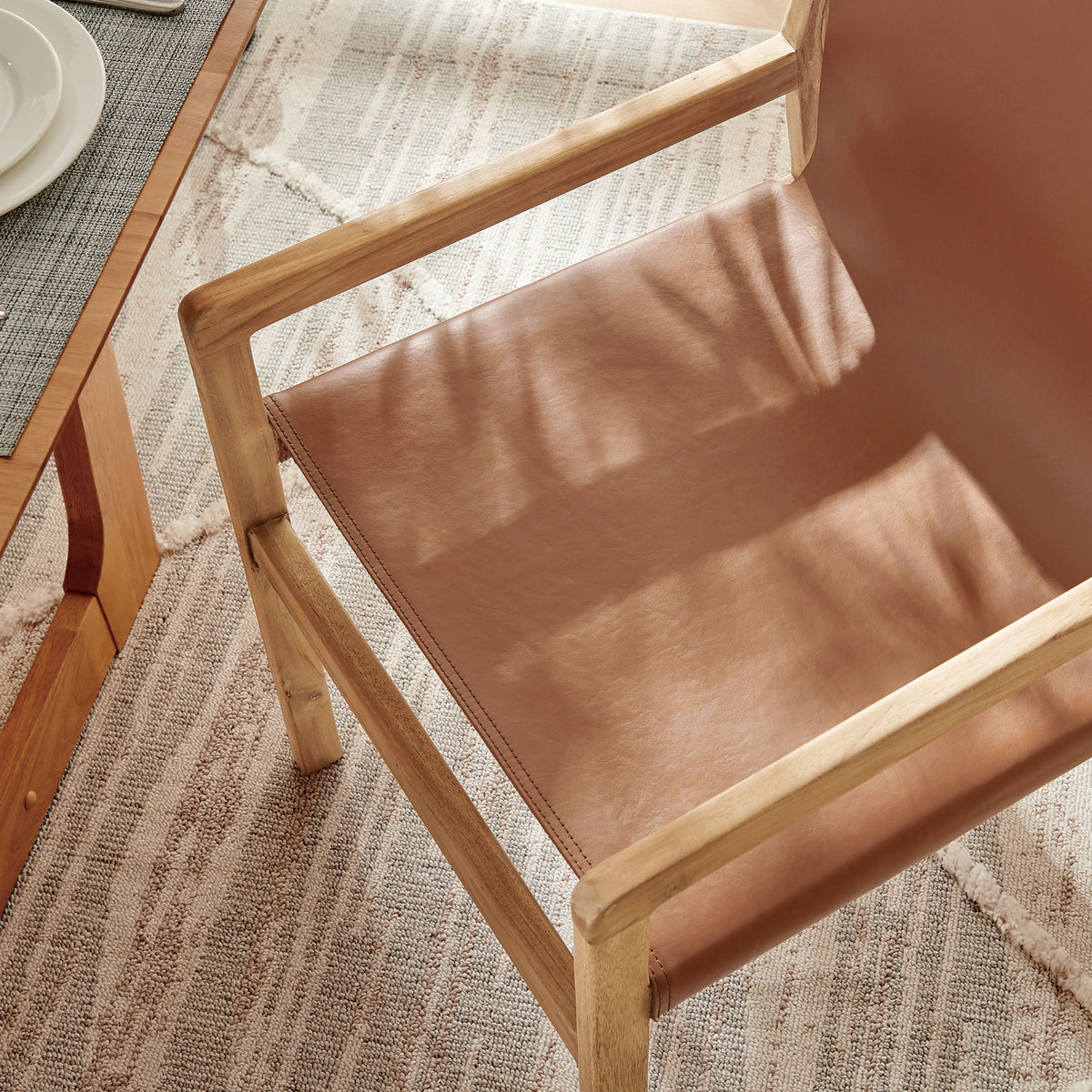 Leather seat catches natural light, revealing rich chestnut tone above a textured neutral rug || EEI-7325-CSN || detail_room