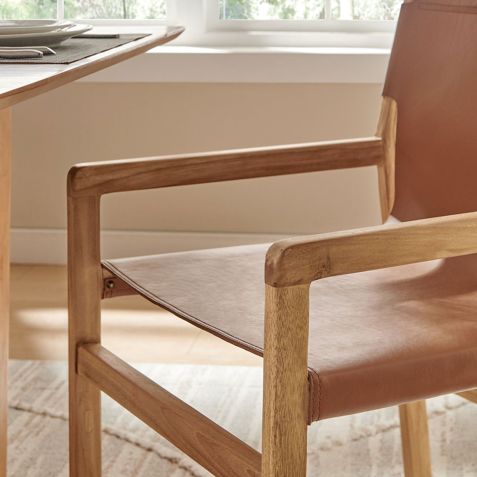 Teak armrest of Sonora chair beside a dining table, blending warm wood tones in a cozy setting || EEI-7325-CSN || detail_room