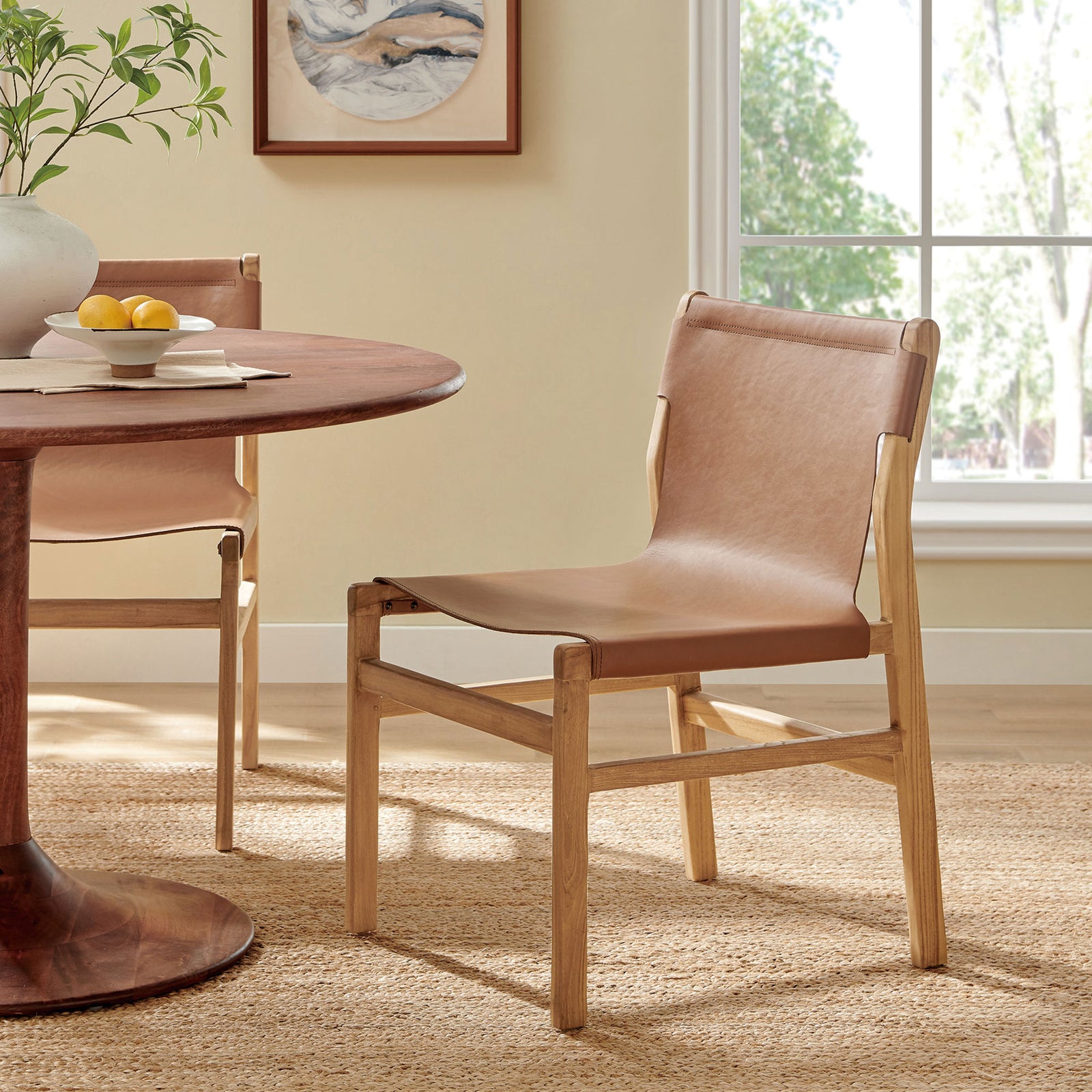 Sonora leather dining side chair beside a round table, bringing modern organic warmth to the dining space || EEI-7326-CSN || front_angle_room