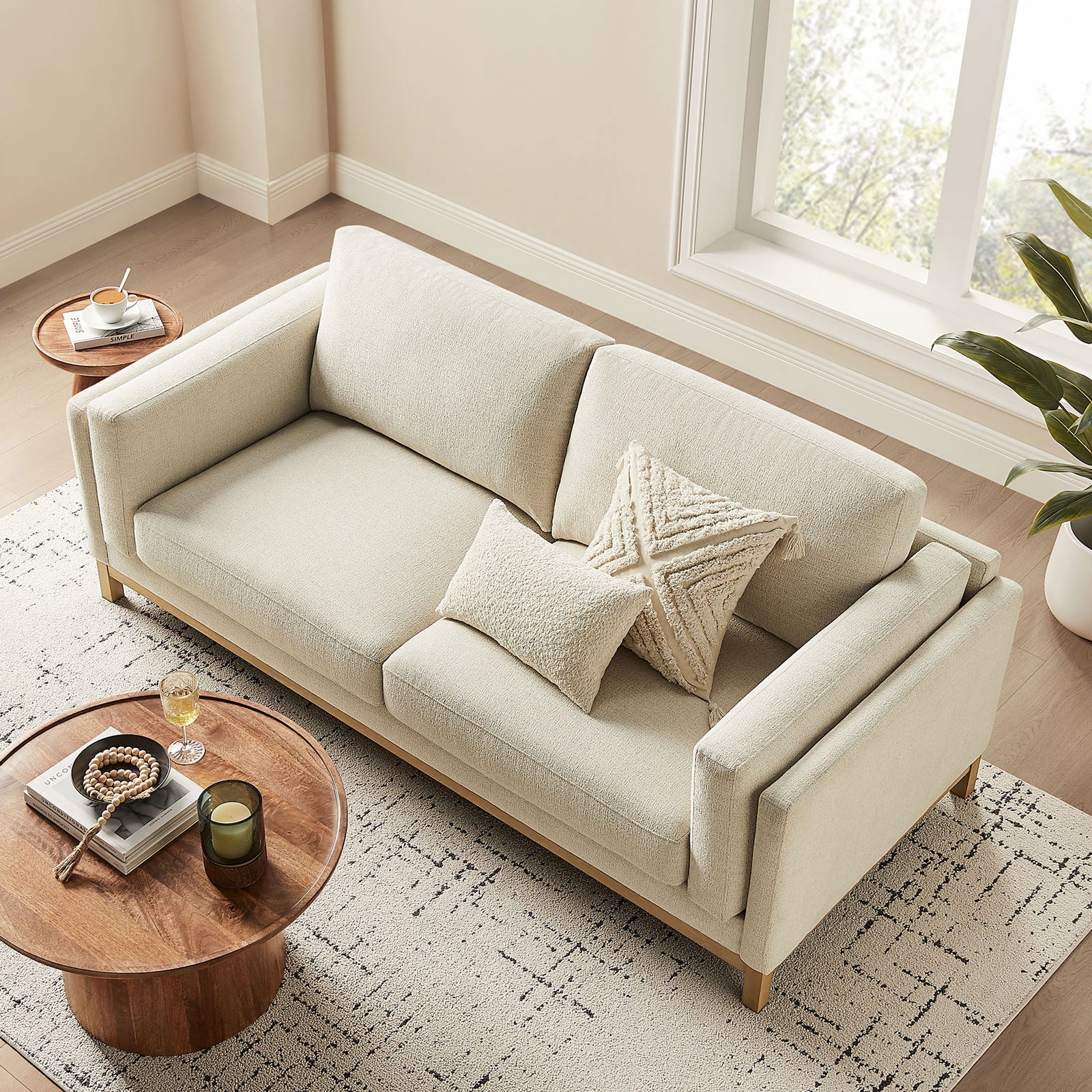 Roscoe sofa arranged with cozy throw pillows beside a round wood coffee table in a sunlit room || EEI-7327-IVO || top_angle_room