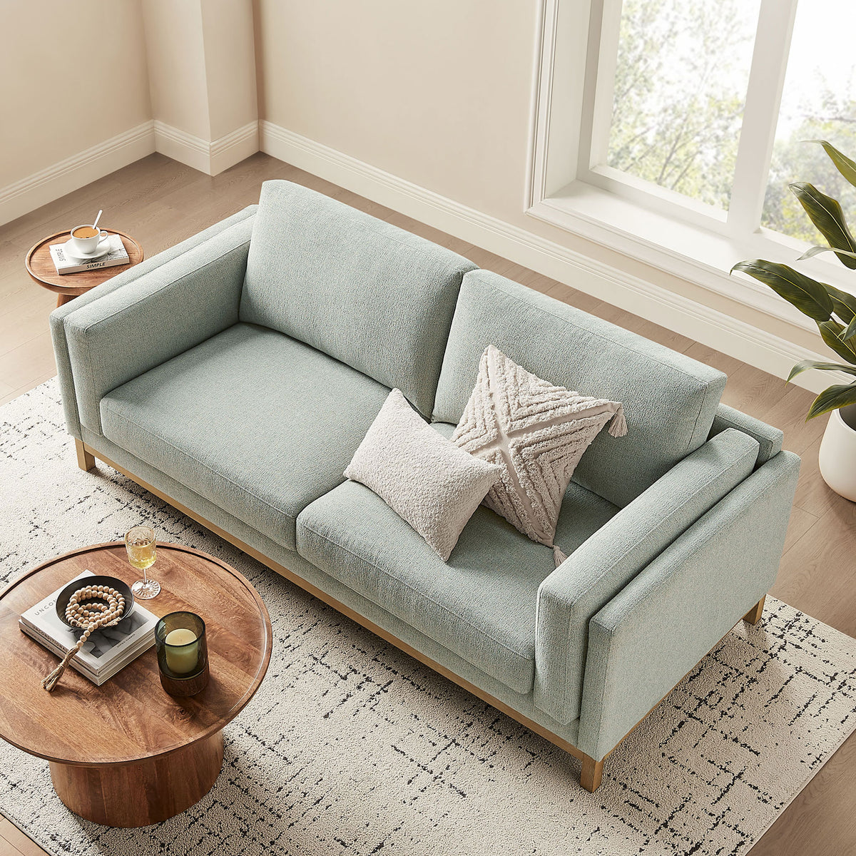 Roscoe mist sofa showcasing spacious seat cushions and textured accent pillows in a bright room || EEI-7327-MST || top_angle_room